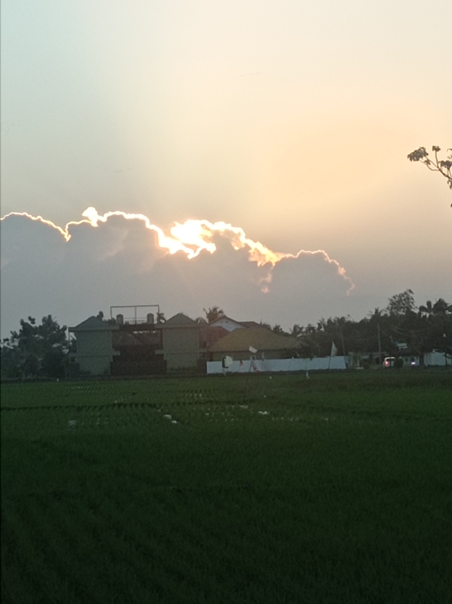 Golden sunset breaks through clouds over rural Kelurahan Oluhuta Utara