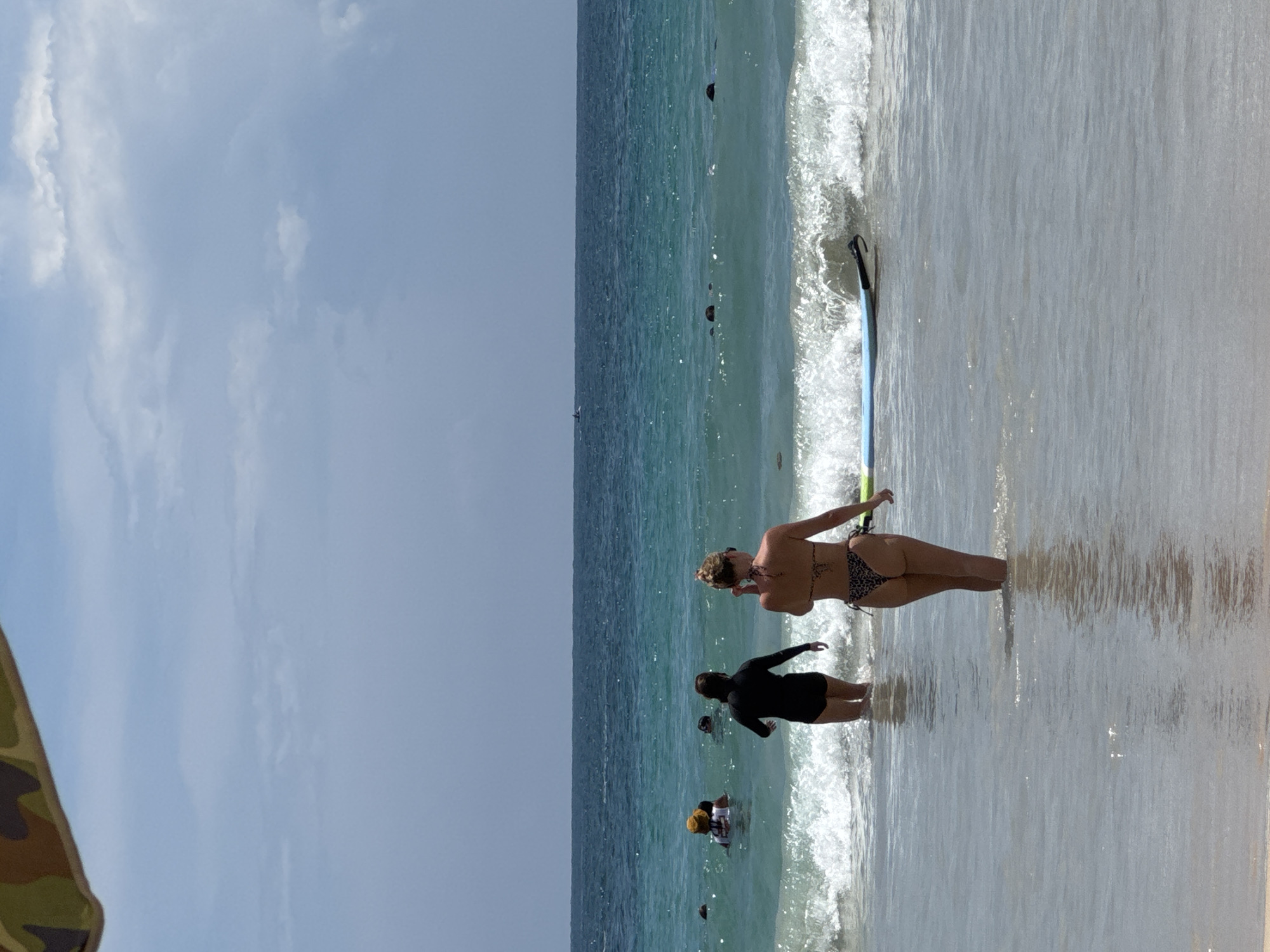Calm morning at Karon Beach with surfers wading in.