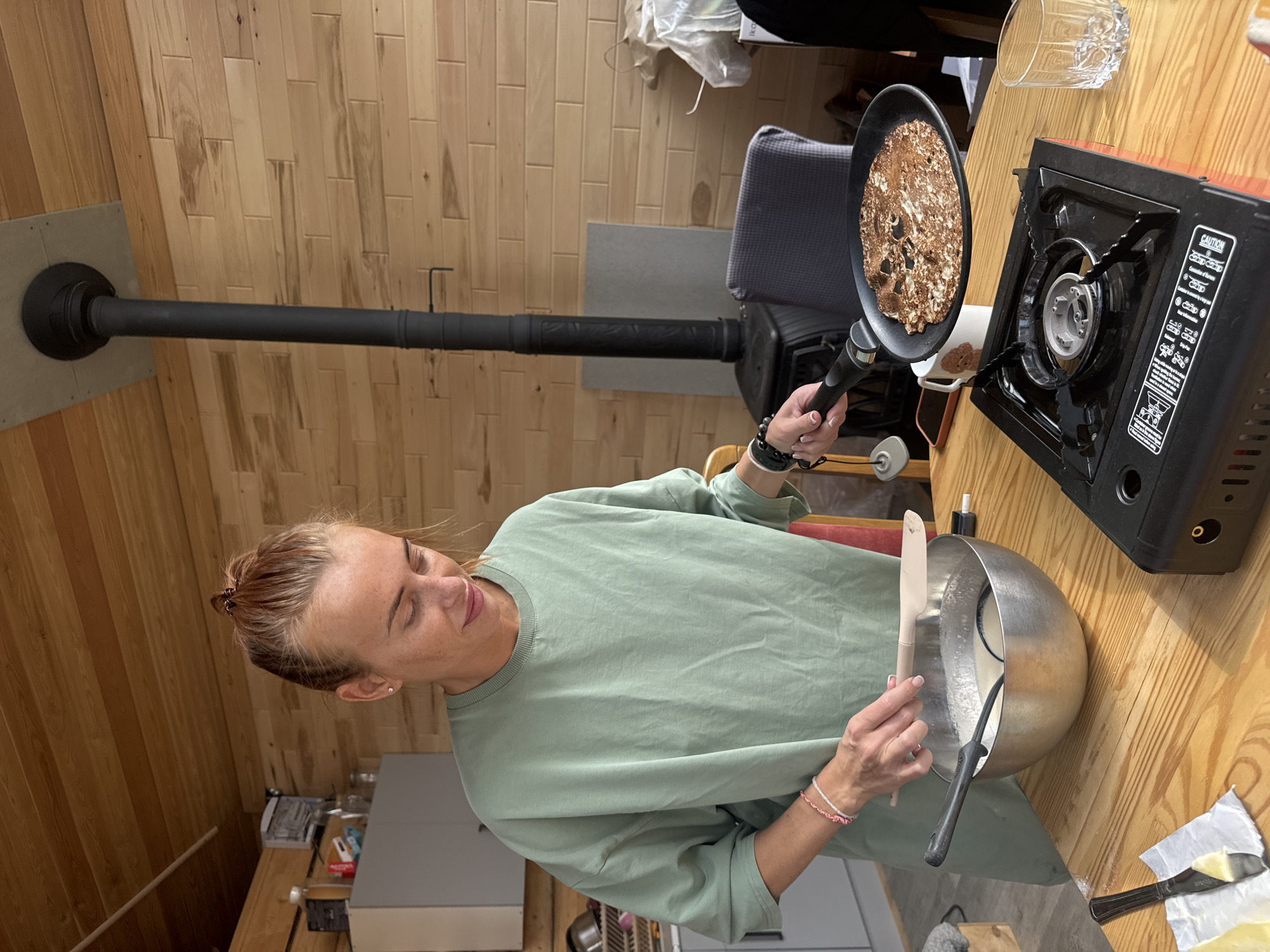 Woman cooks pancakes in early morning kitchen in Russia
