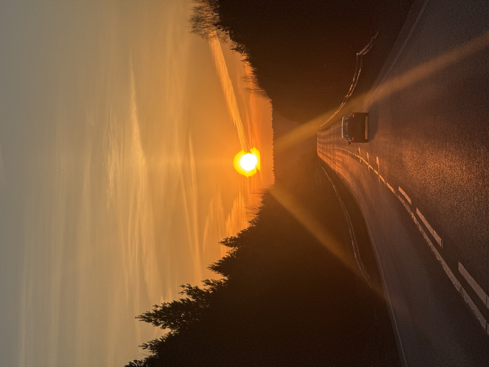 Car drives toward sunset on Chaikovsky road