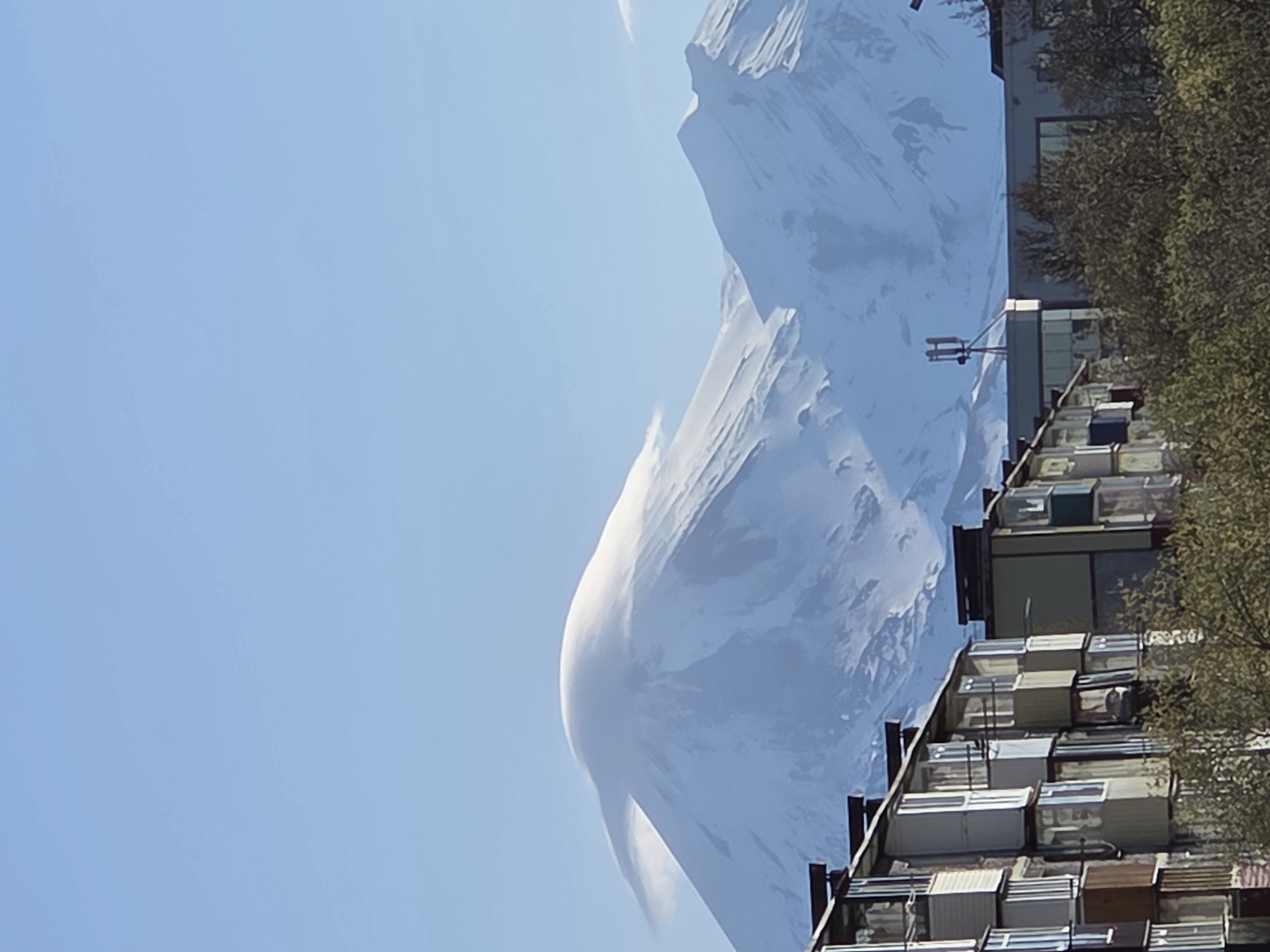City life beneath snow-capped peaks documented in evening light