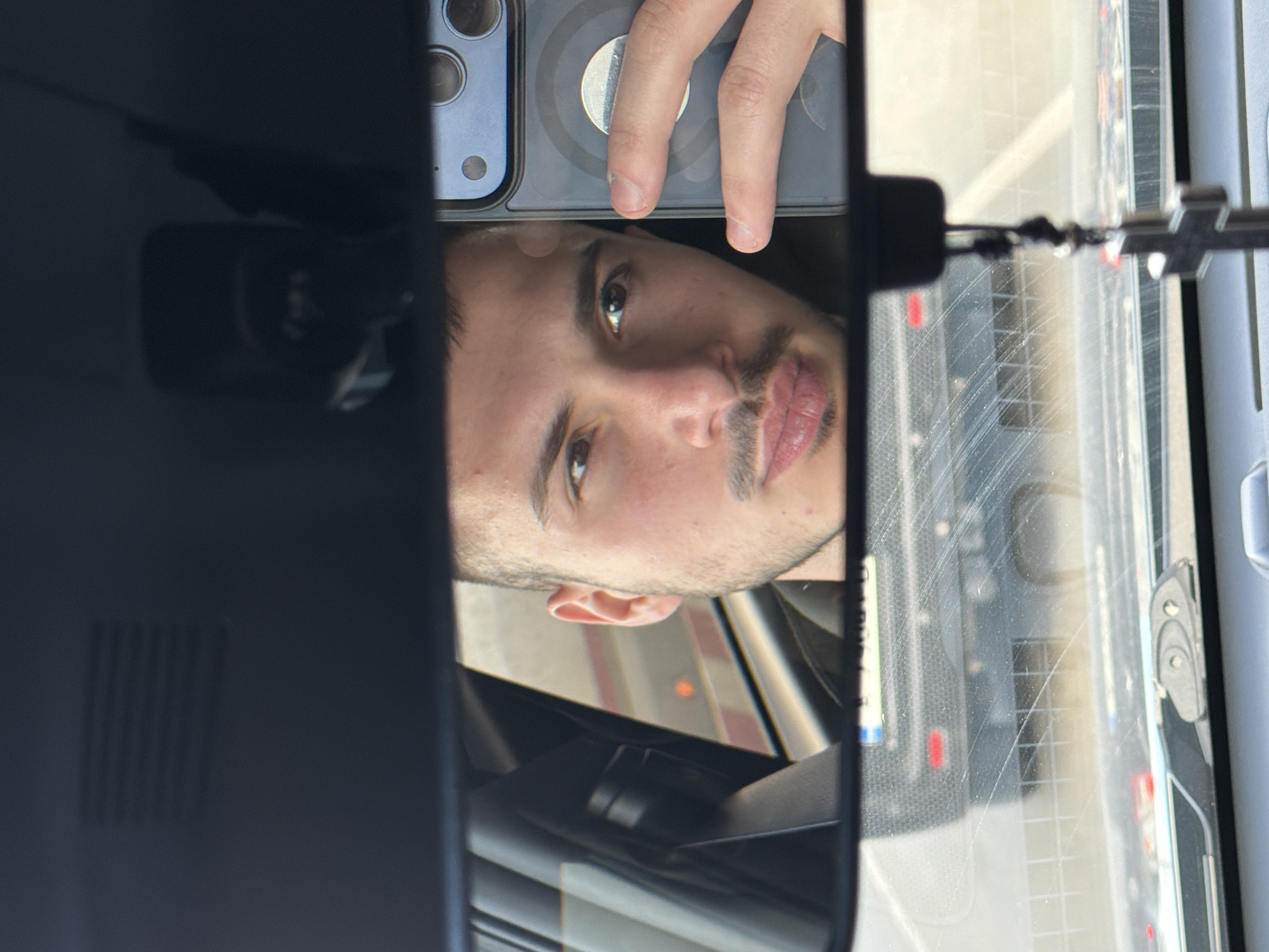 Man uses phone in car captured in rearview mirror reflection