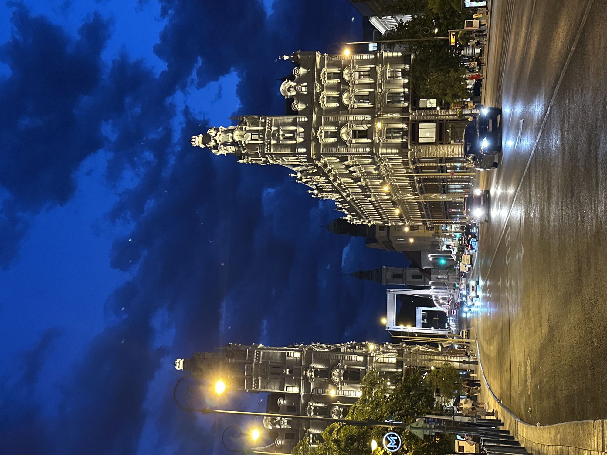 Budapest's grand boulevard glows at dusk under a stormy sky