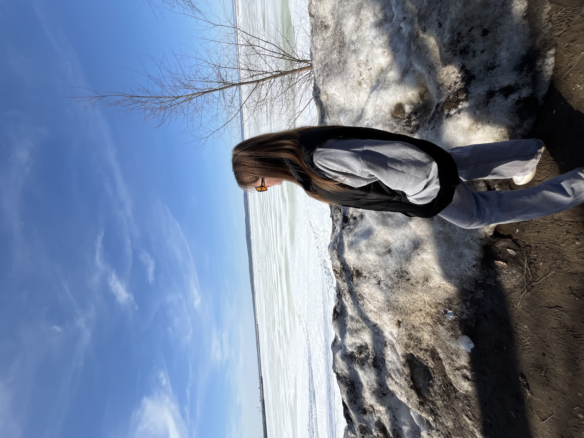 Woman explores snowy Chaikovsky park and reservoir during spring thaw