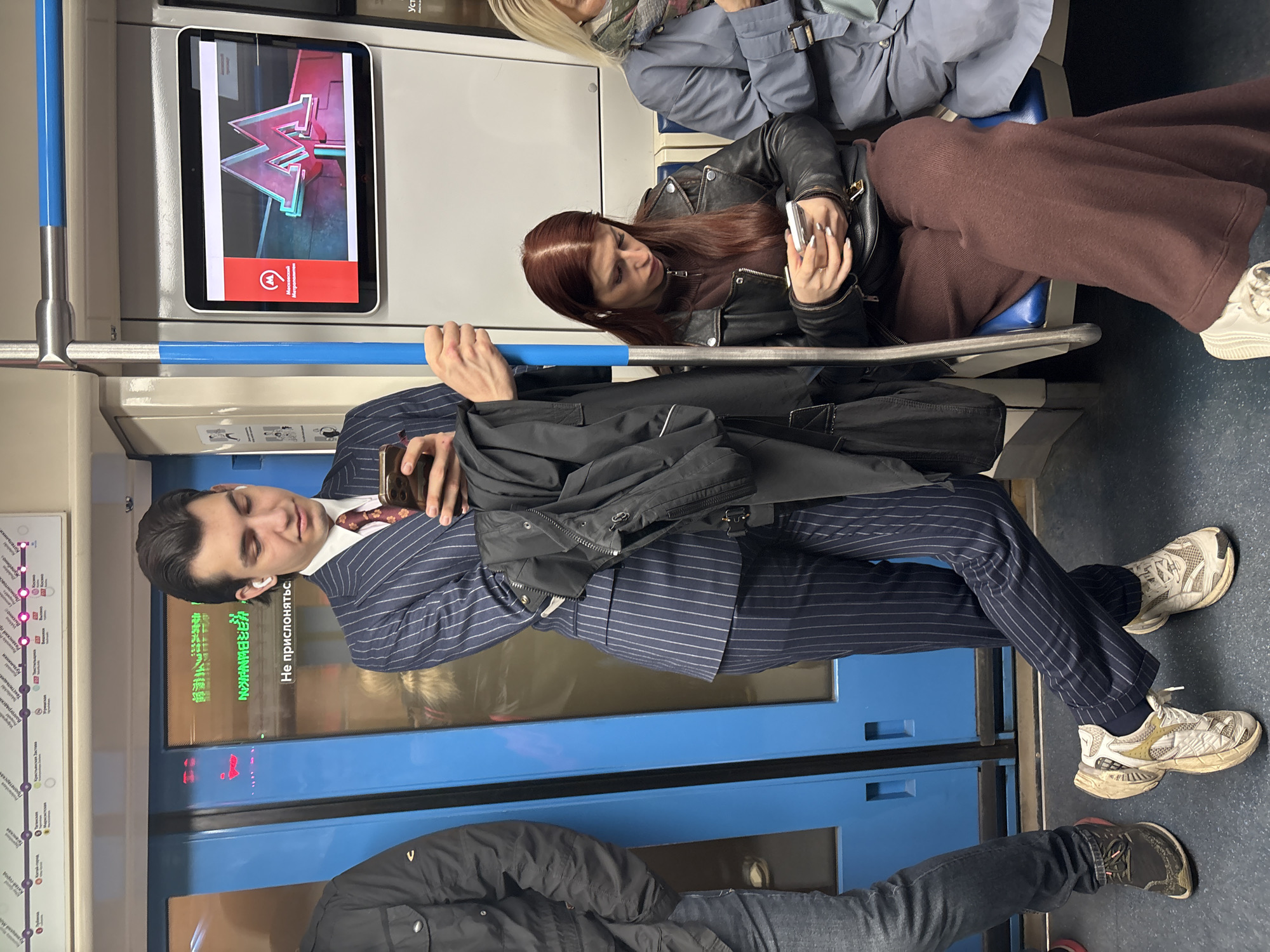 Moscow commuter checks phone during subway ride
