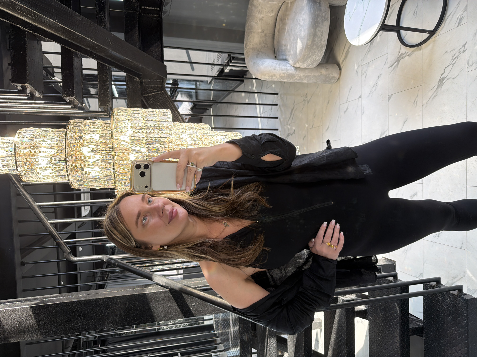 Woman takes selfie on staircase near chandelier in Moscow