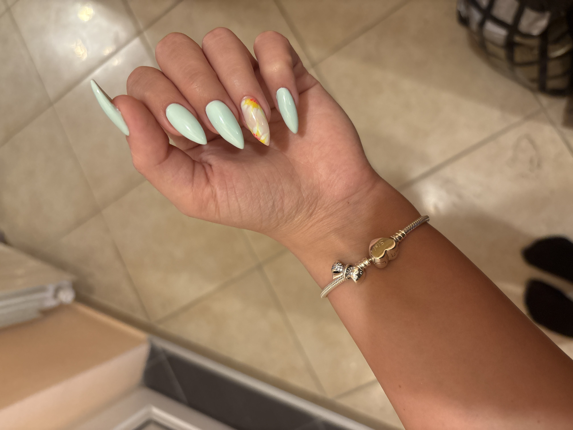 Stiletto nails in pale mint green, tiled floor backdrop