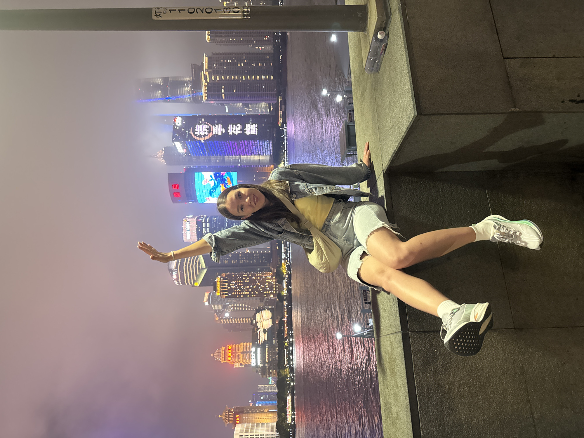 Woman poses against Shanghai skyline backdrop in nighttime photo