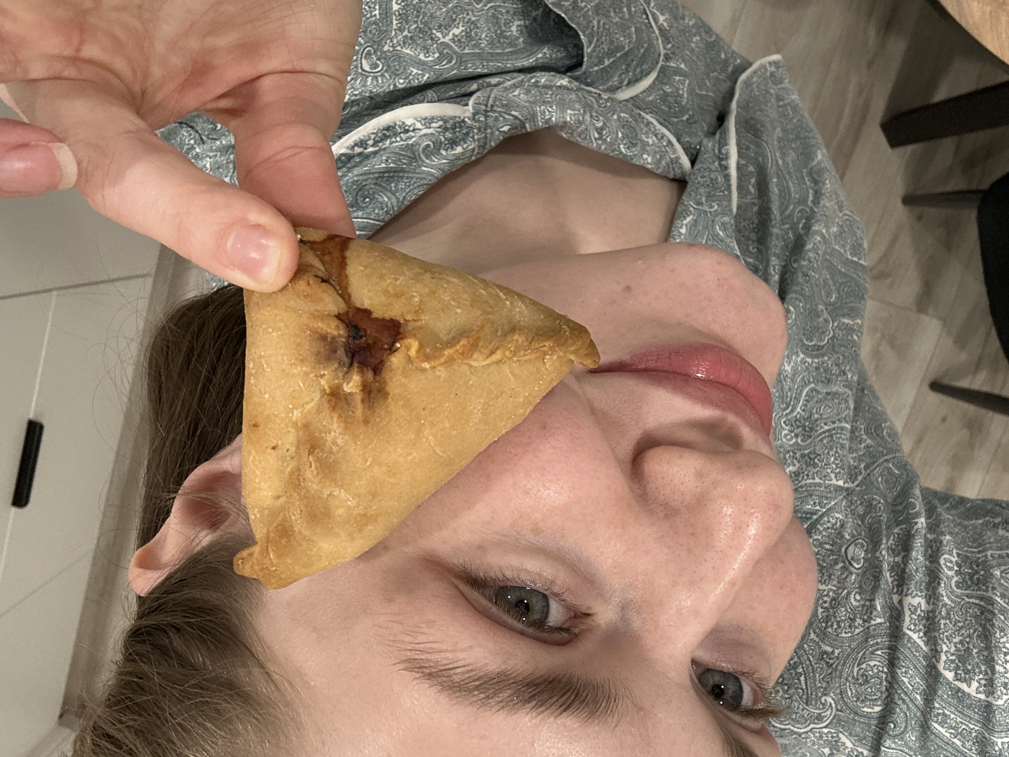 Person enjoys homemade triangular pastries in Kazan kitchen