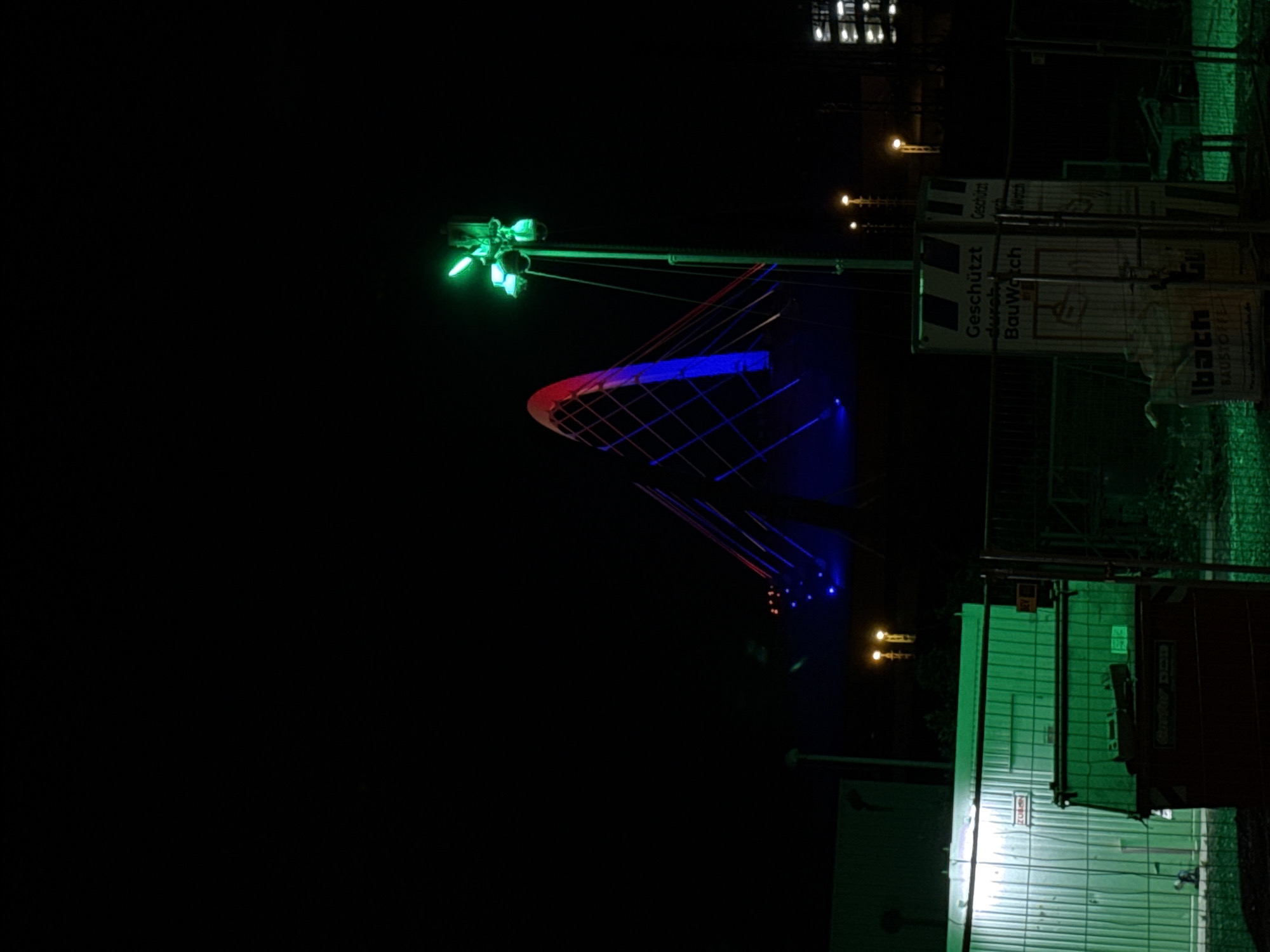 Cologne bridge lit in red-blue with construction equipment visible