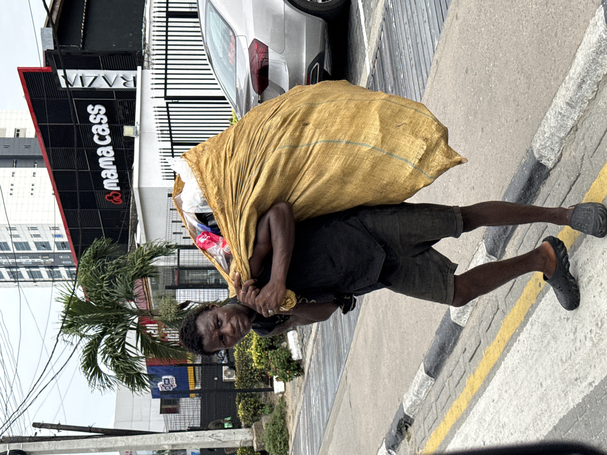Man with yellow bag walks past Mama Cass building