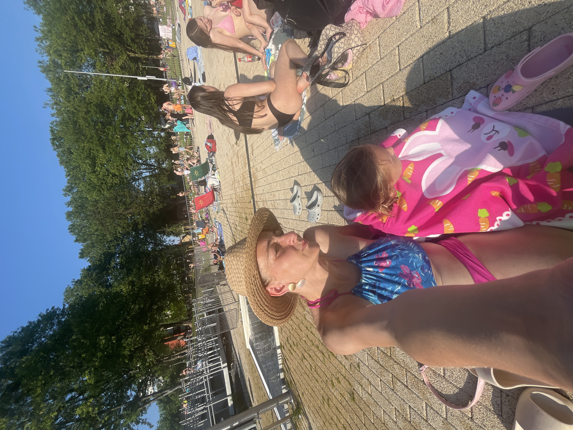 Crowded outdoor pool day with kids, inflatables, and a ladybug