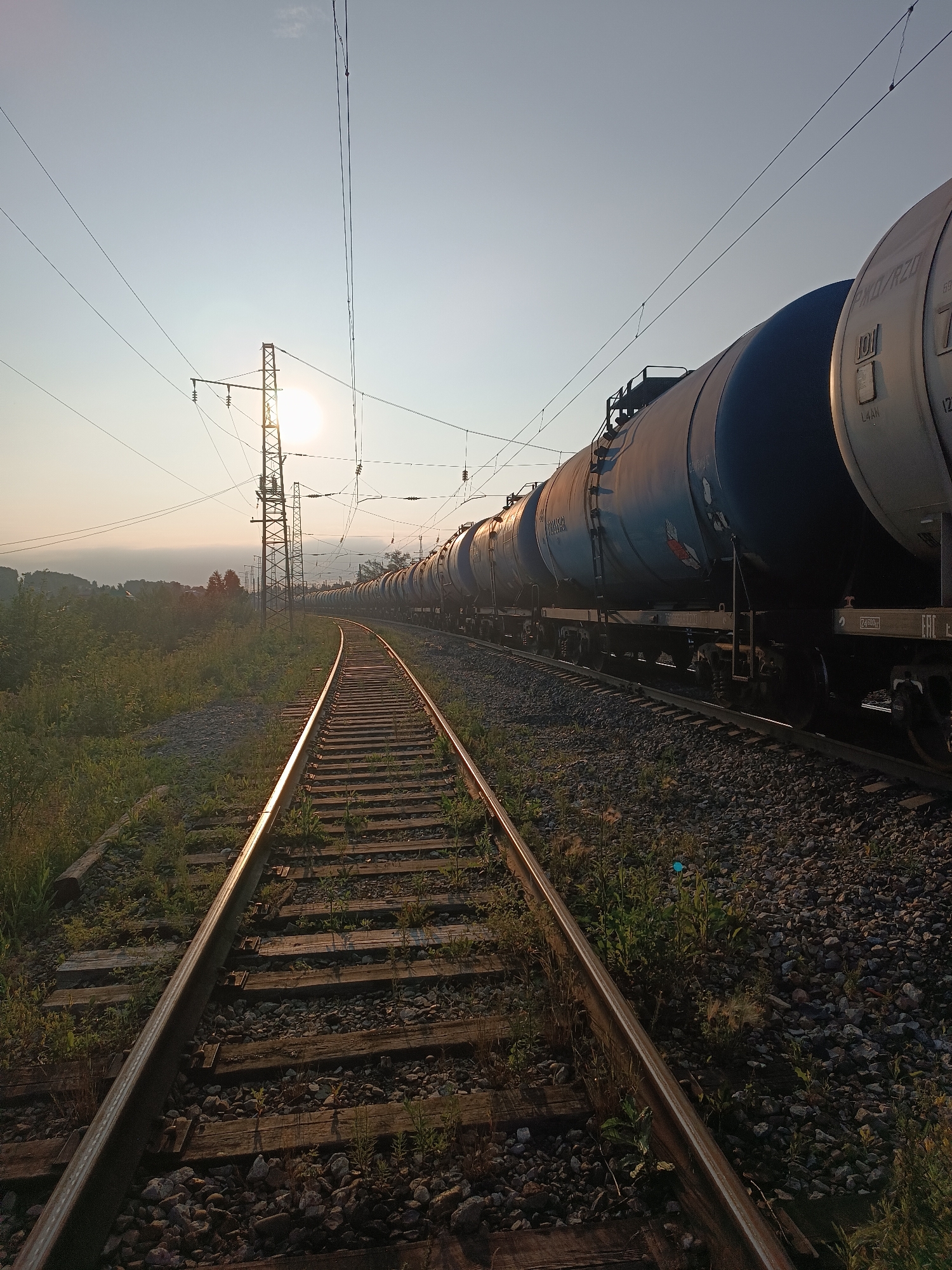 Blue tank car freight train curves through open rail country