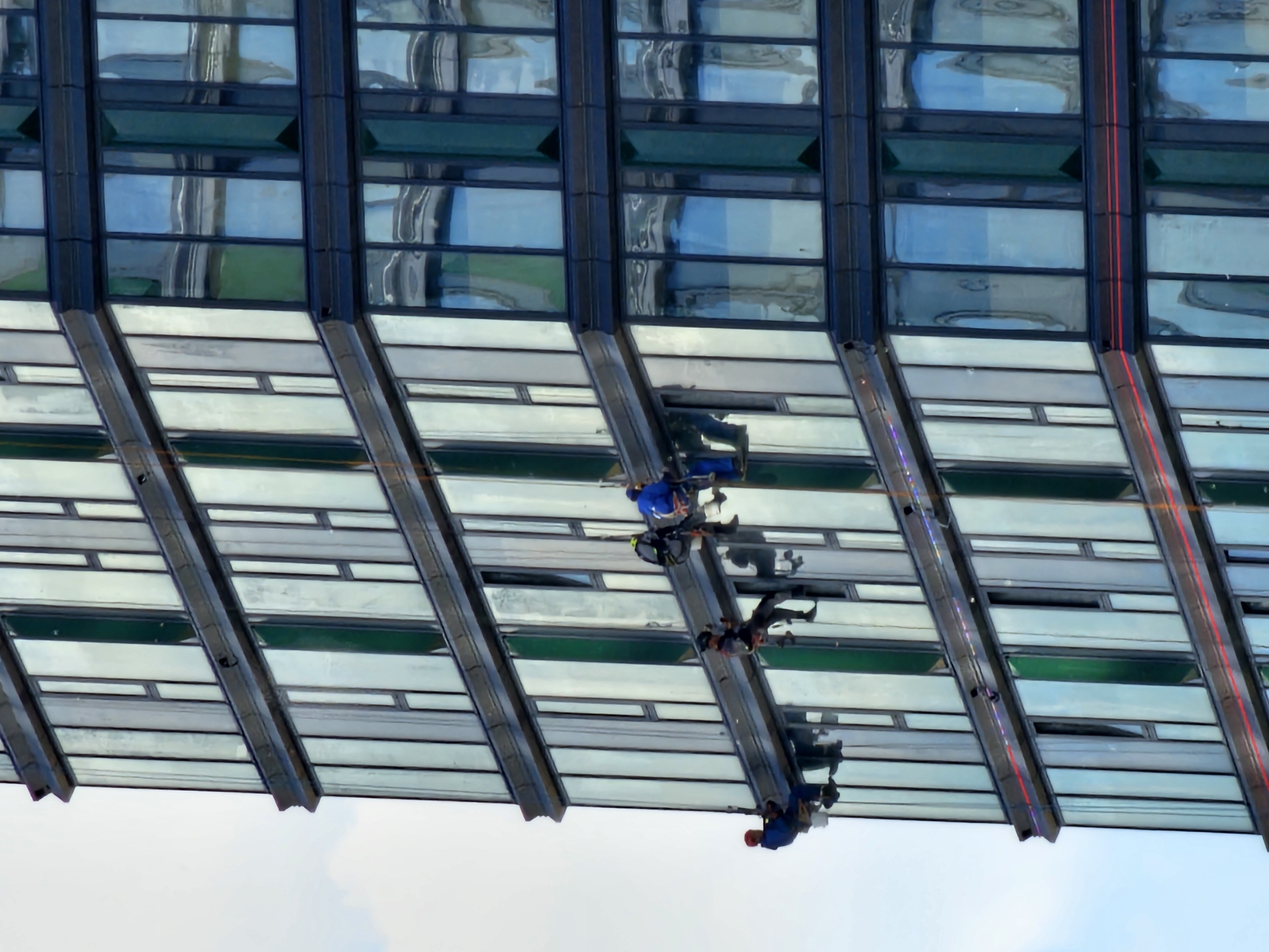Window cleaners work Moscow skyscraper as luxury cars park below