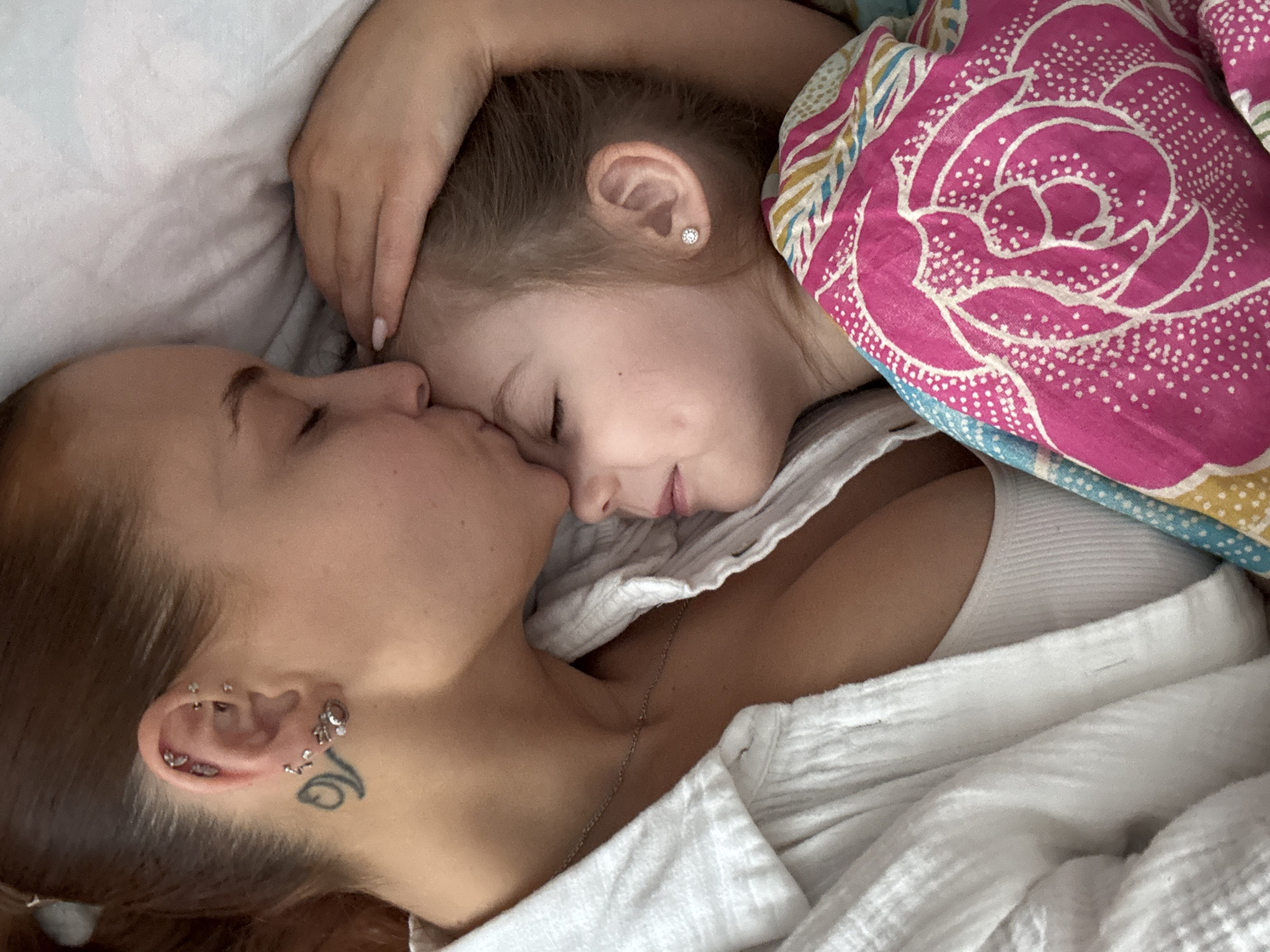 Mother and daughter share tender morning moment in bed