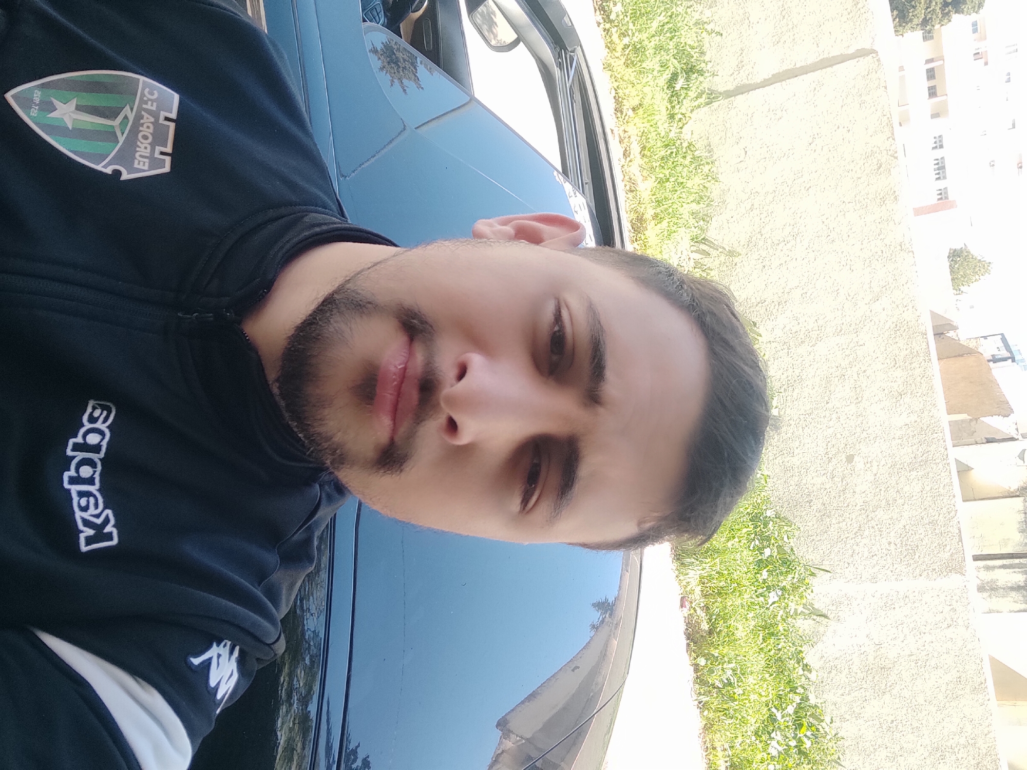 Man in team jacket stands by car in Meknes