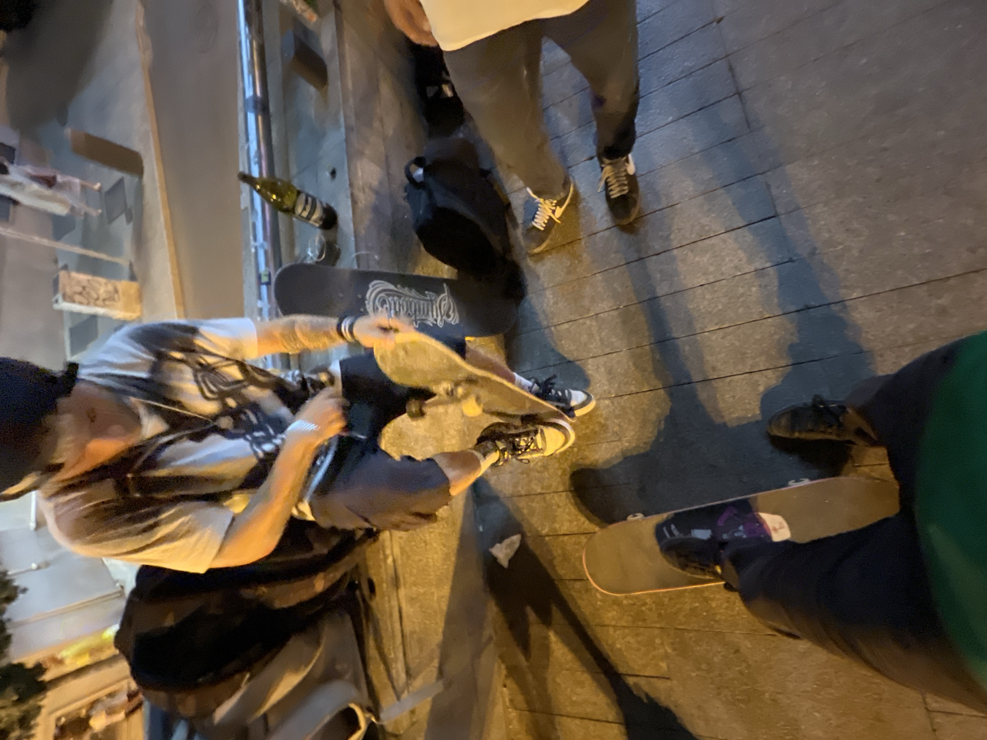Small group hanging out on a Madrid sidewalk, summer evening