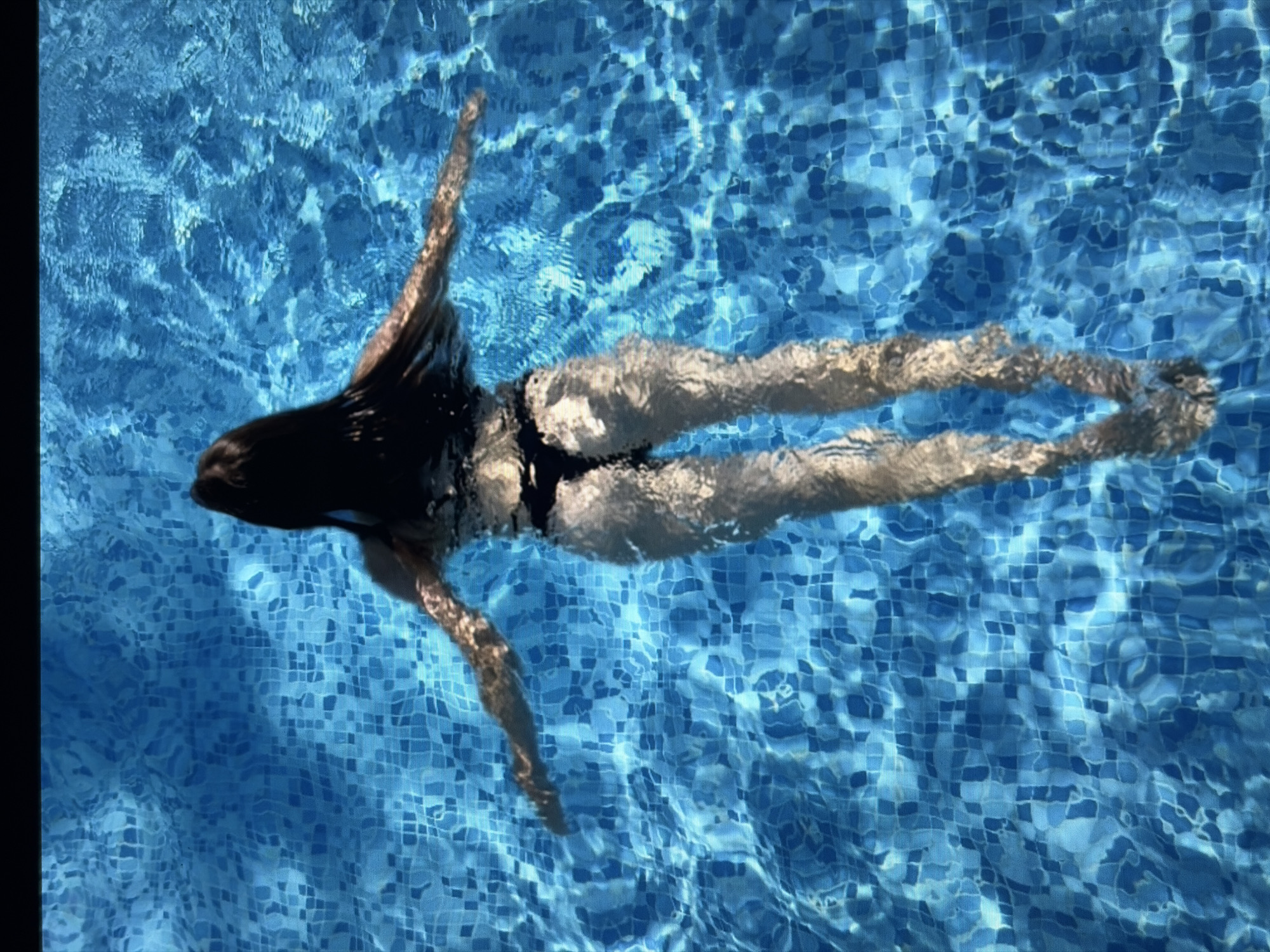 Floating on back in a blue tiled swimming pool