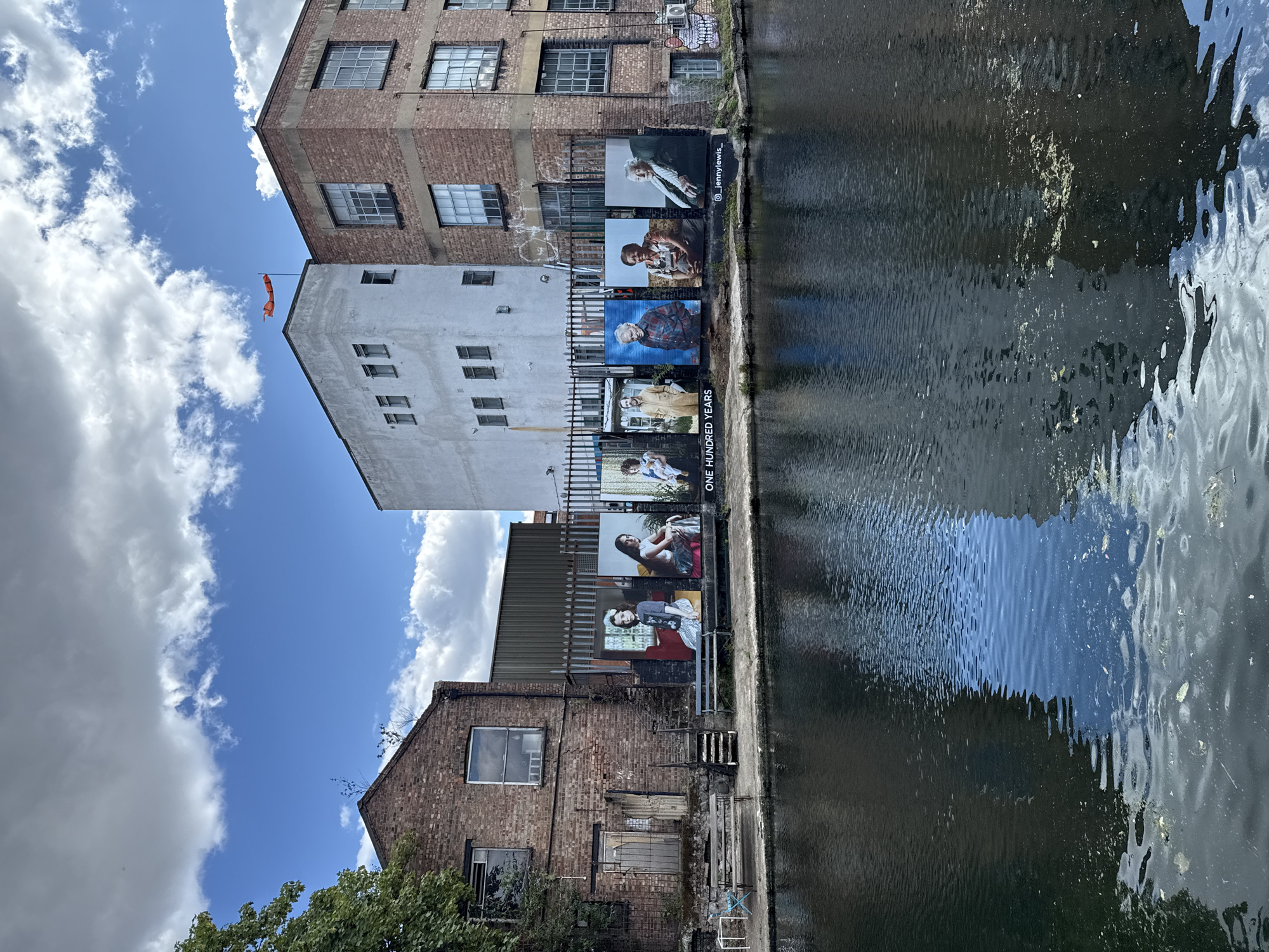 Large portrait exhibition lines a London canal-side brick wall