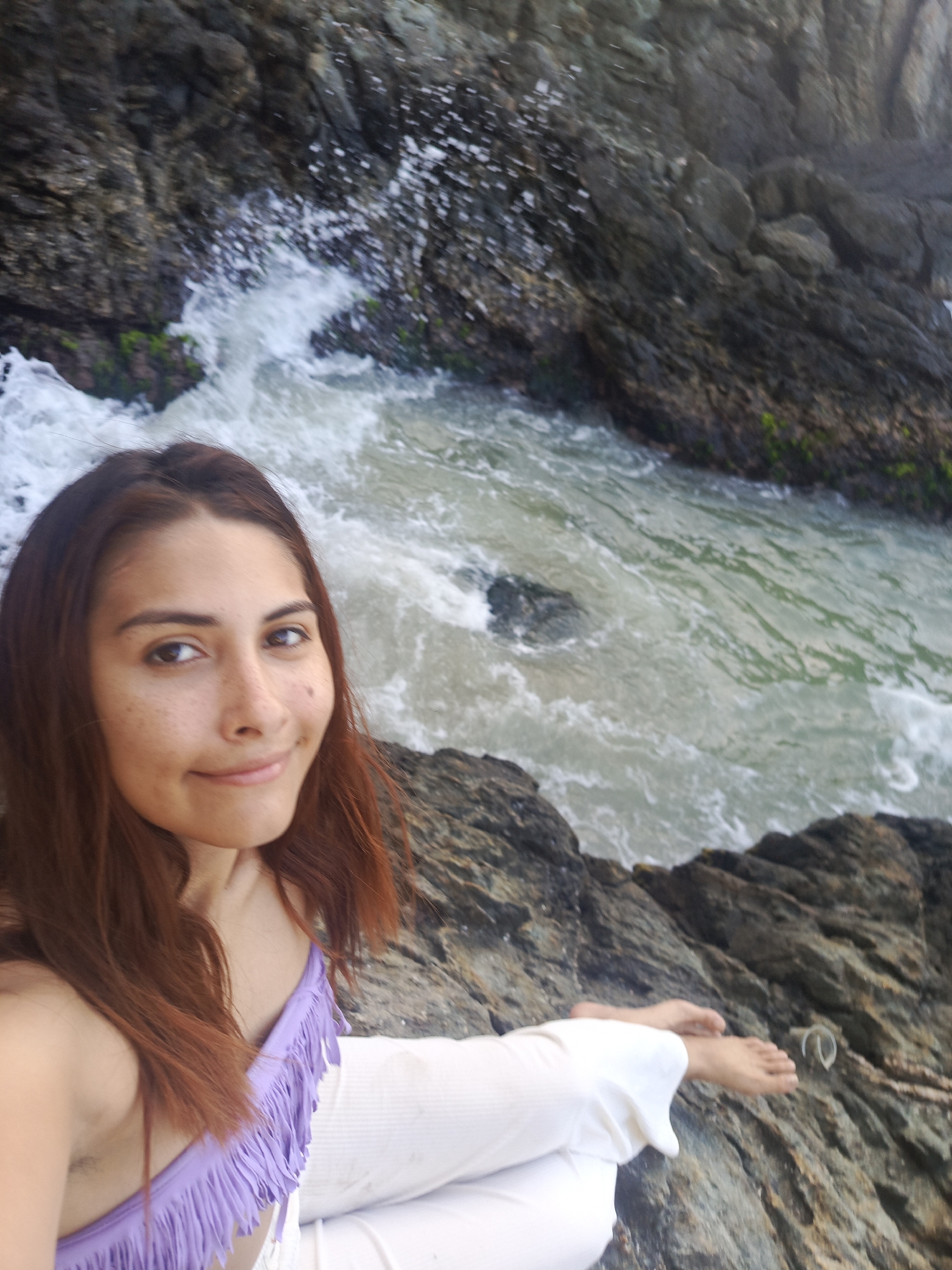 Woman poses for beach photos on rocky shoreline