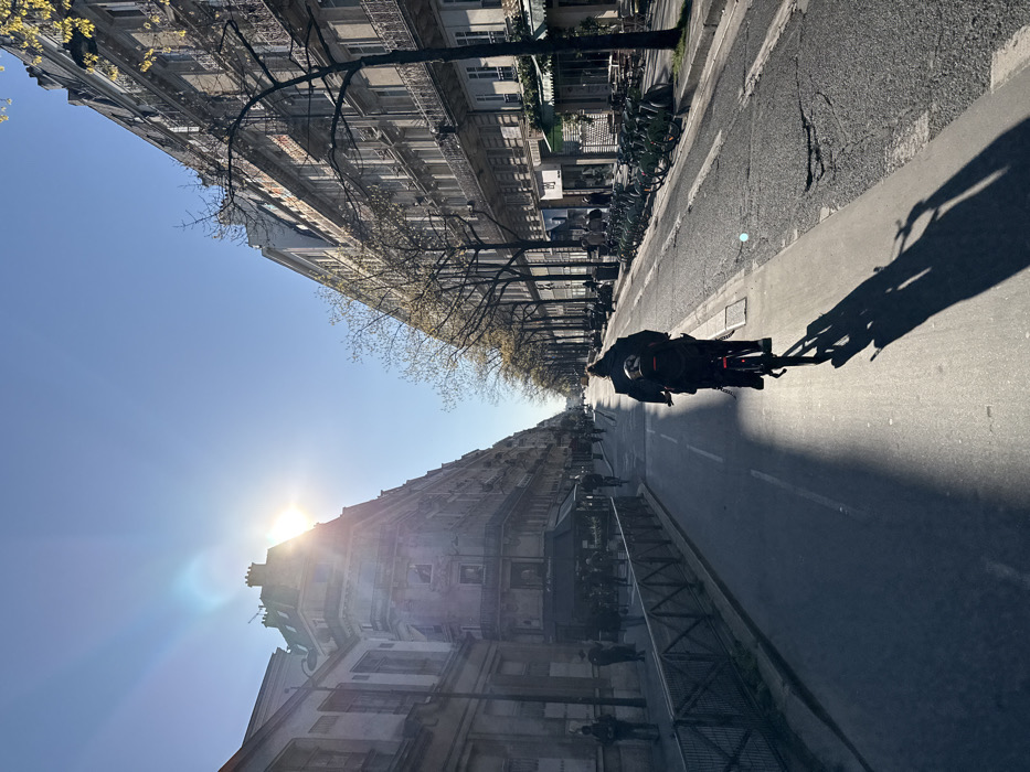 Cyclist observed on Paris street during bright afternoon sun
