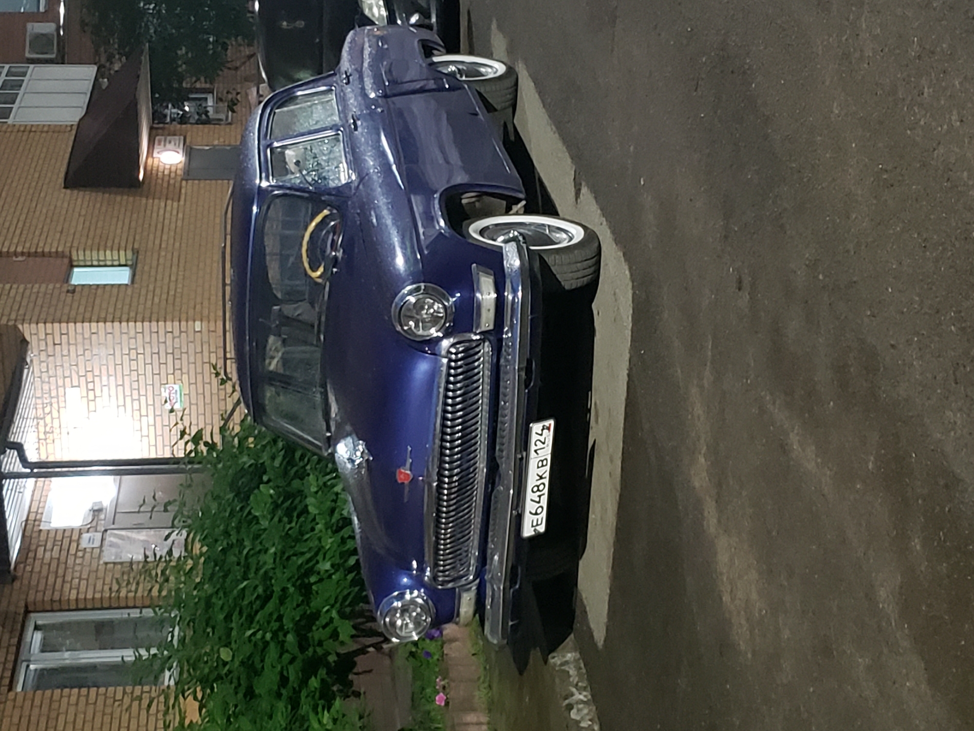 Classic GAZ-21 Volga parked on a wet street at night