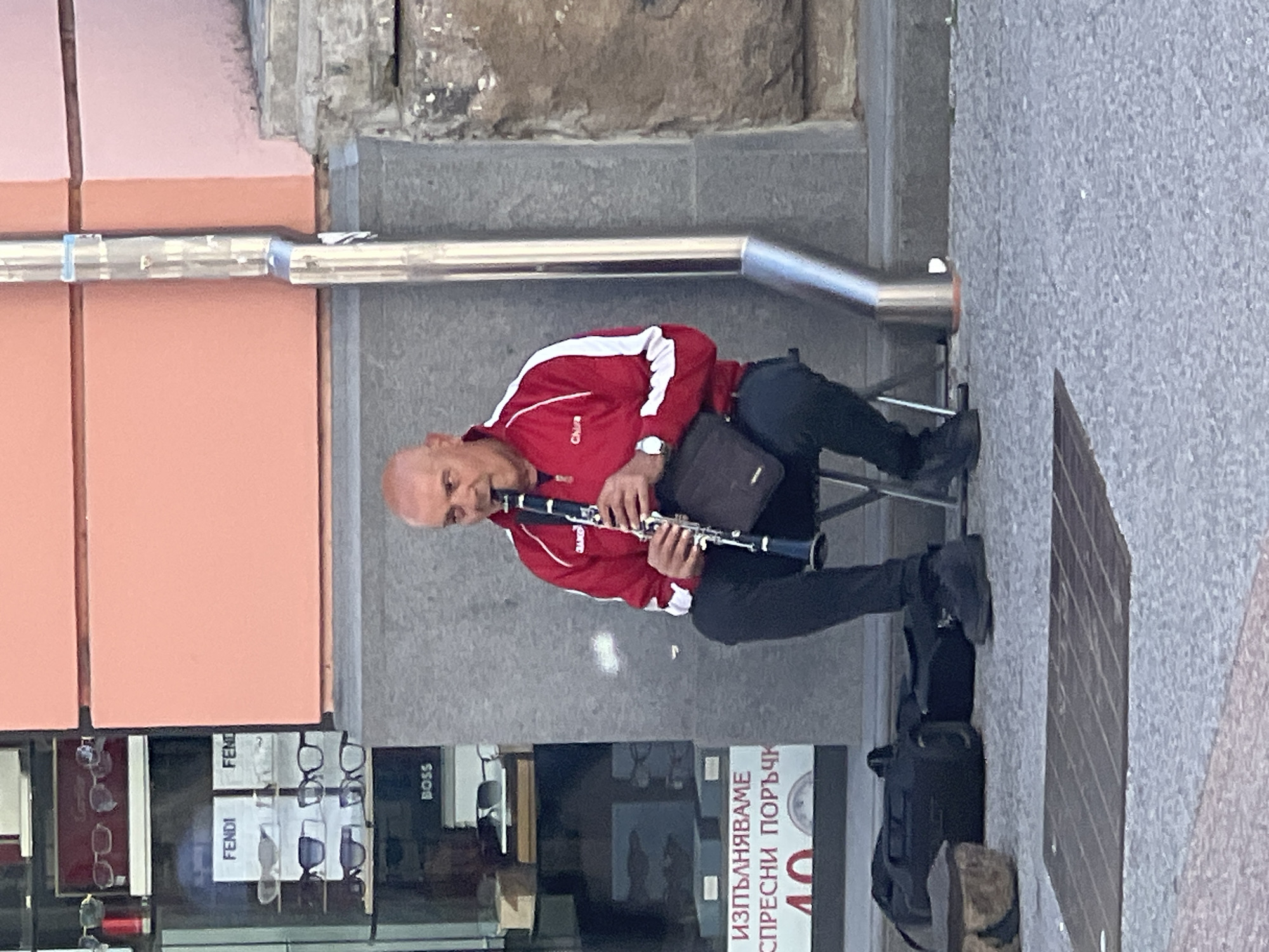 Street musician performs clarinet in urban commercial district