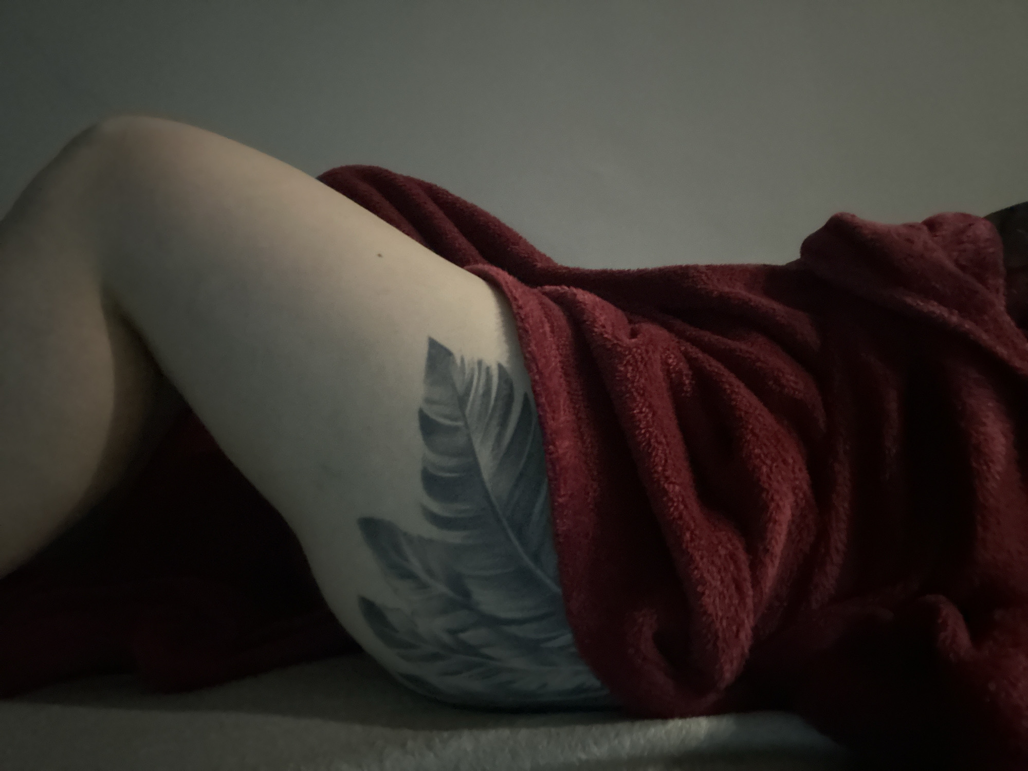 Person with feather tattoo rests in bed in Bulgaria