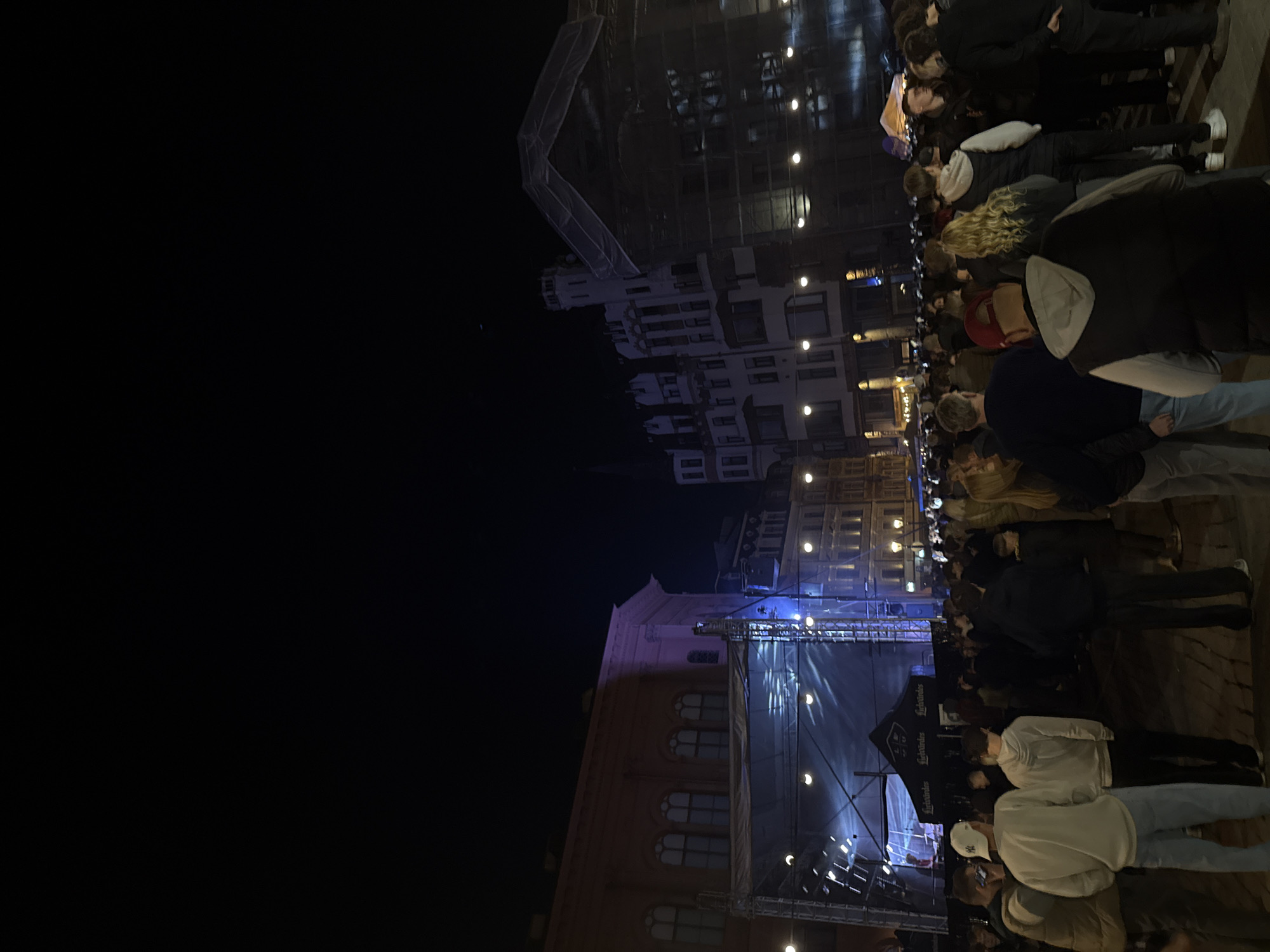 Evening crowd gathers around illuminated stage in Riga square