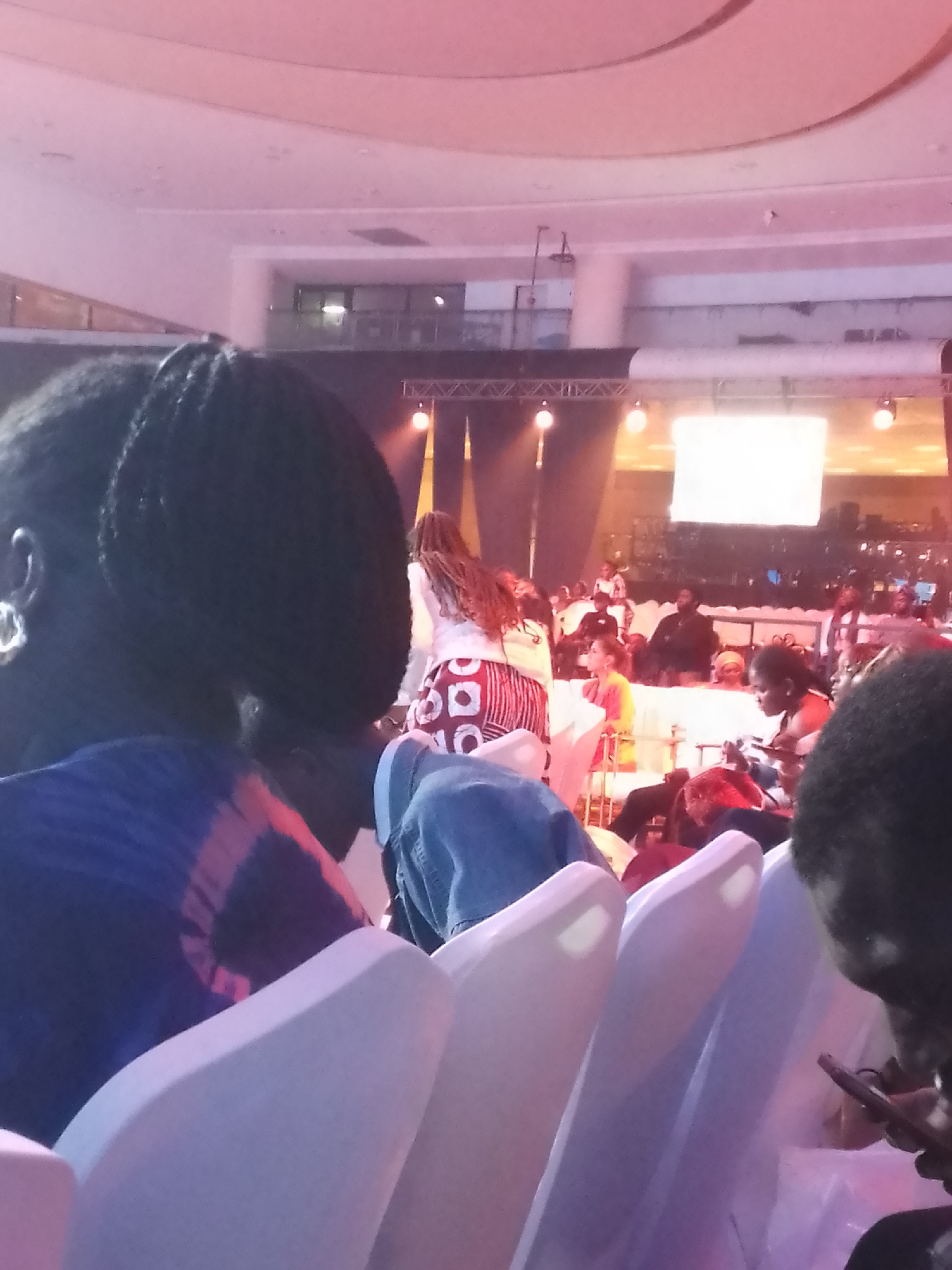 Indoor conference gathering draws seated audience to illuminated stage