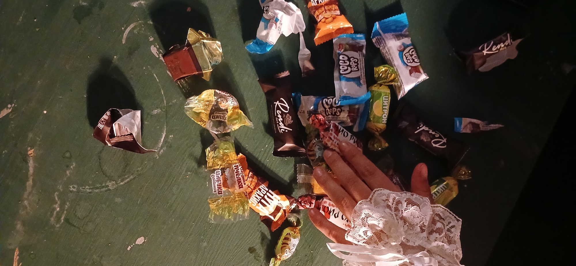Hand reaches for scattered chocolates on Moscow table