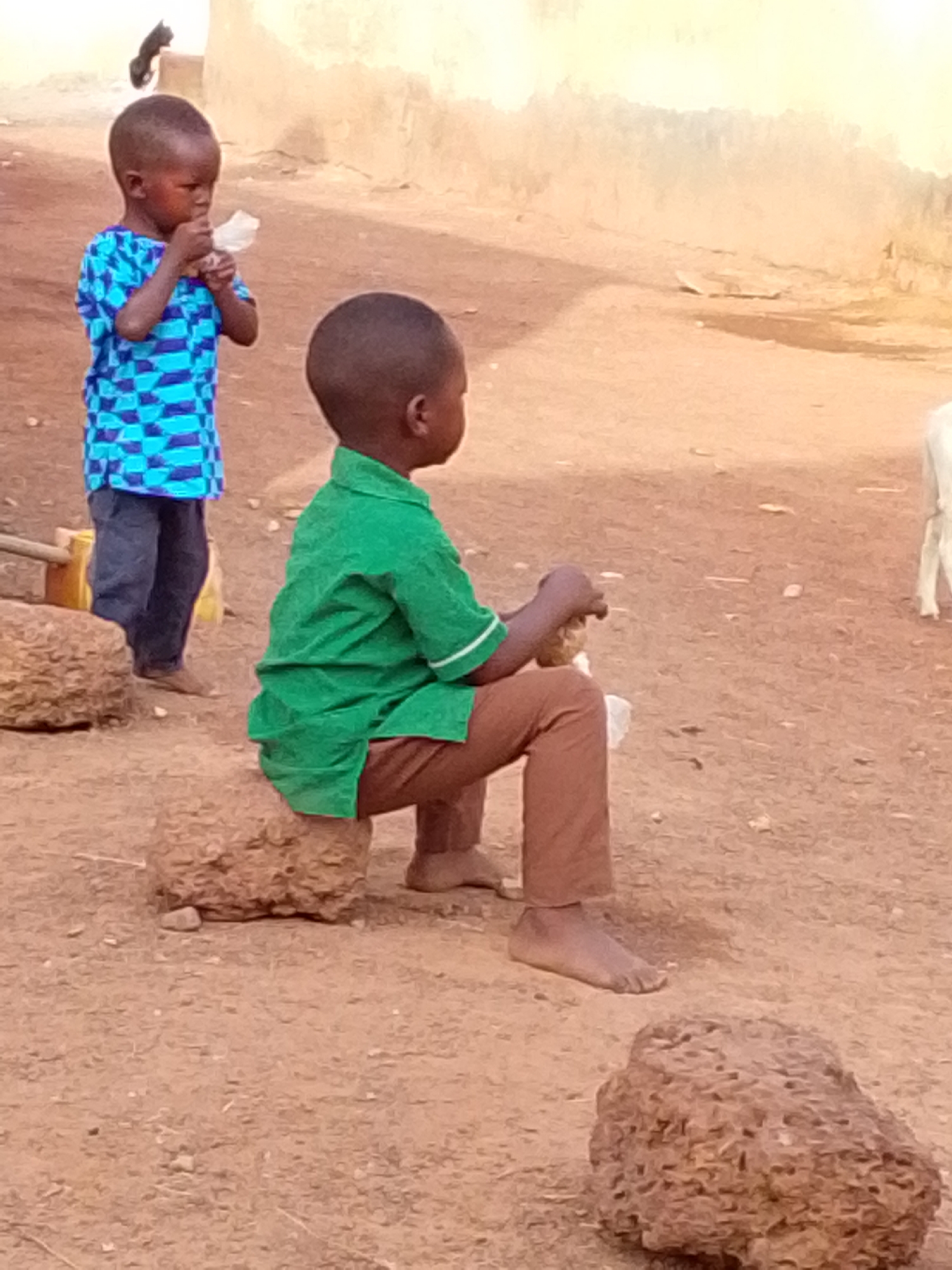 Children play and eat in morning scenes around Tamale