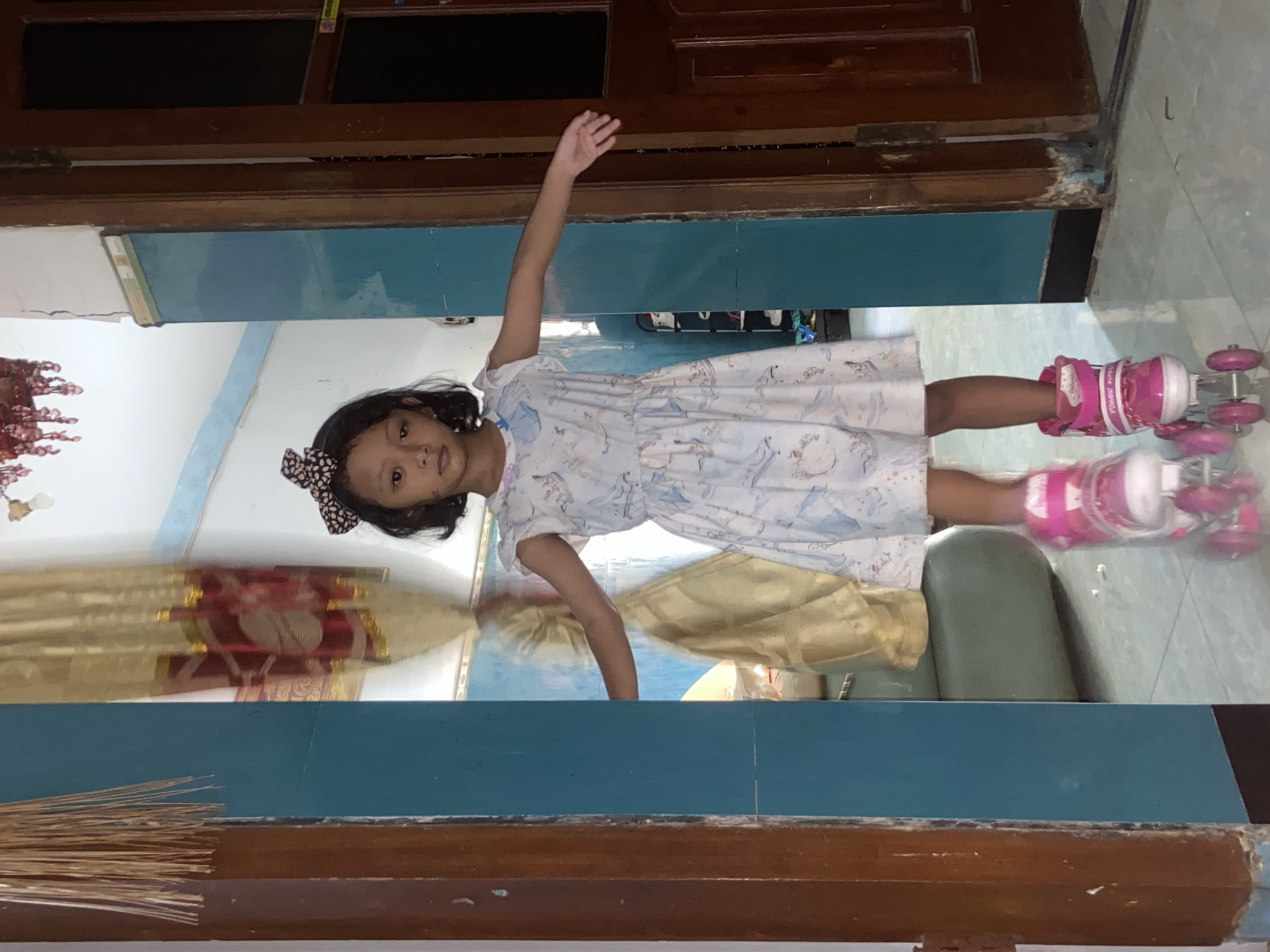 Girl in pink roller skates poses indoors in Gelam