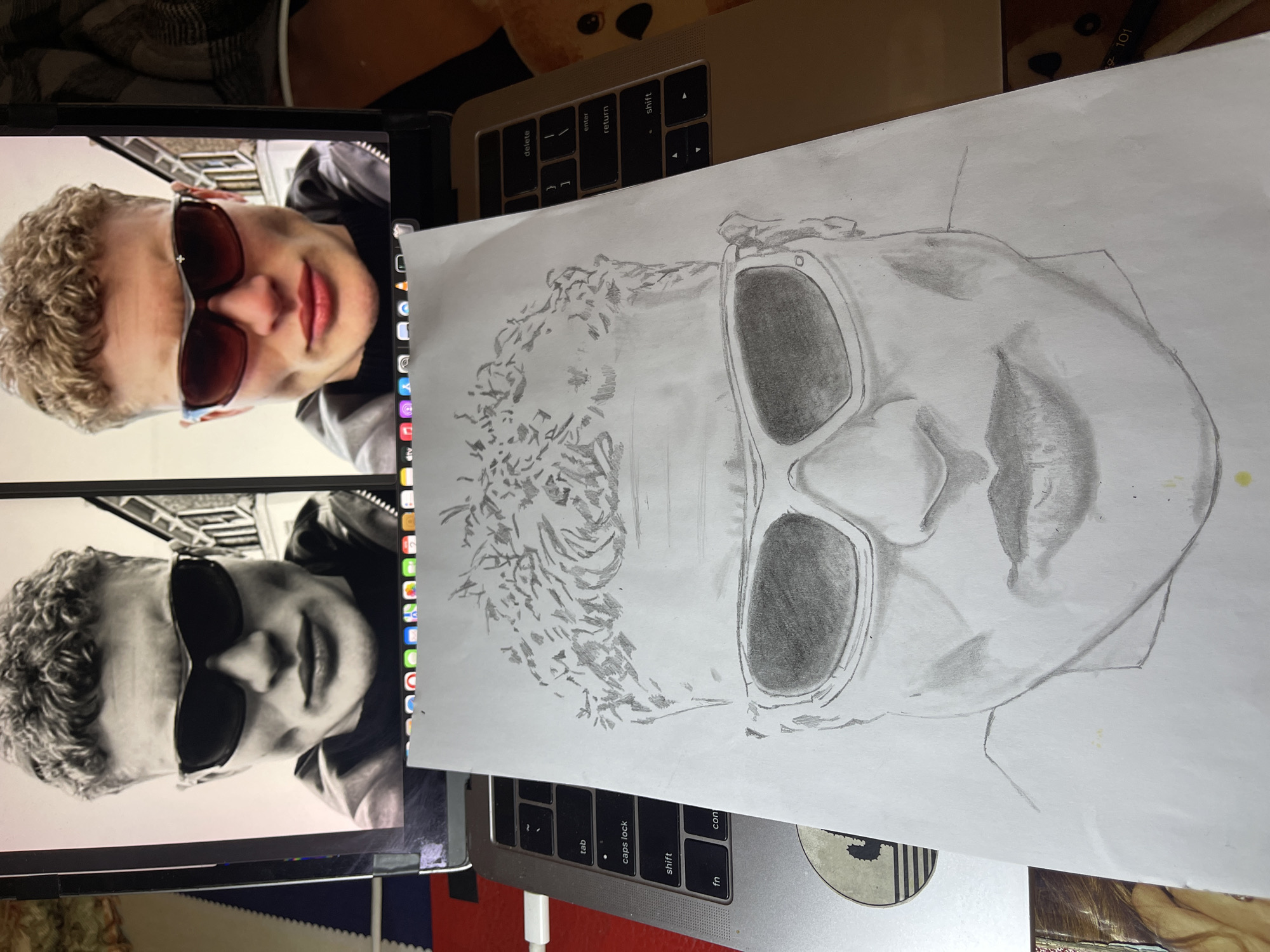 Artist creates portrait sketches using laptop reference images in Jos