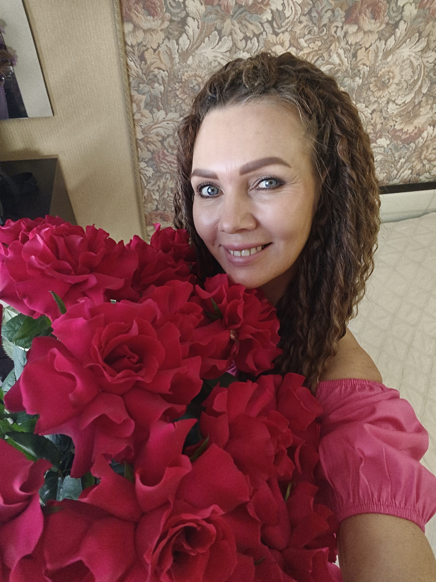 Woman poses with red roses bouquet in interior setting