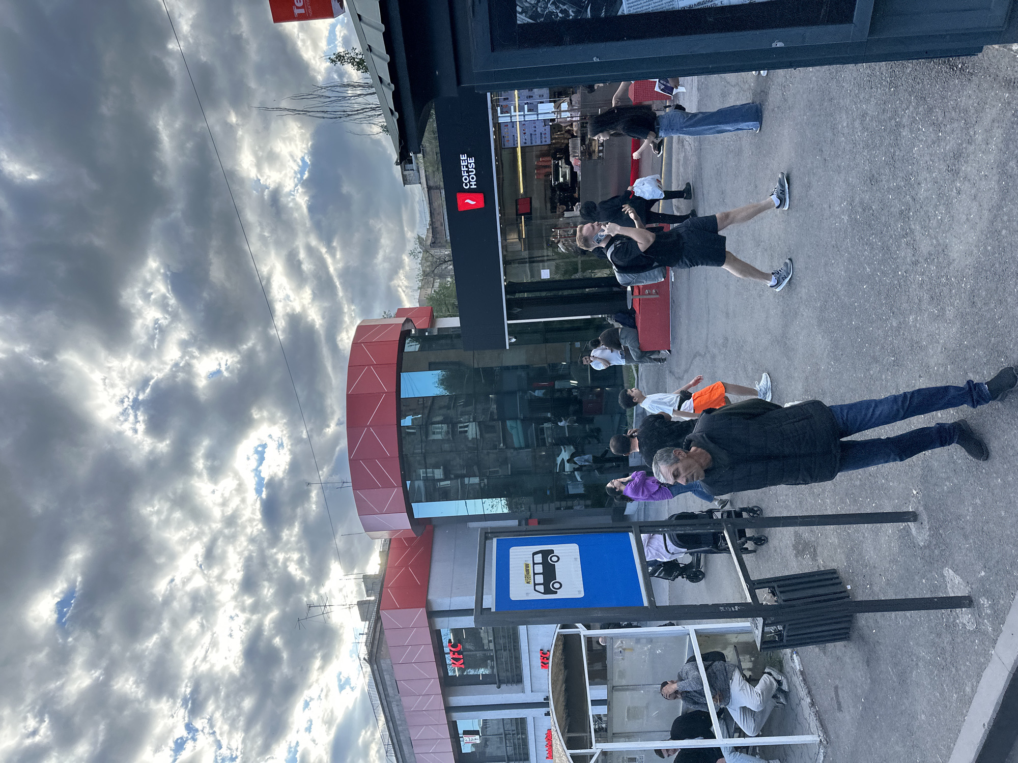 Pedestrians gather at Yerevan bus stop near cafes