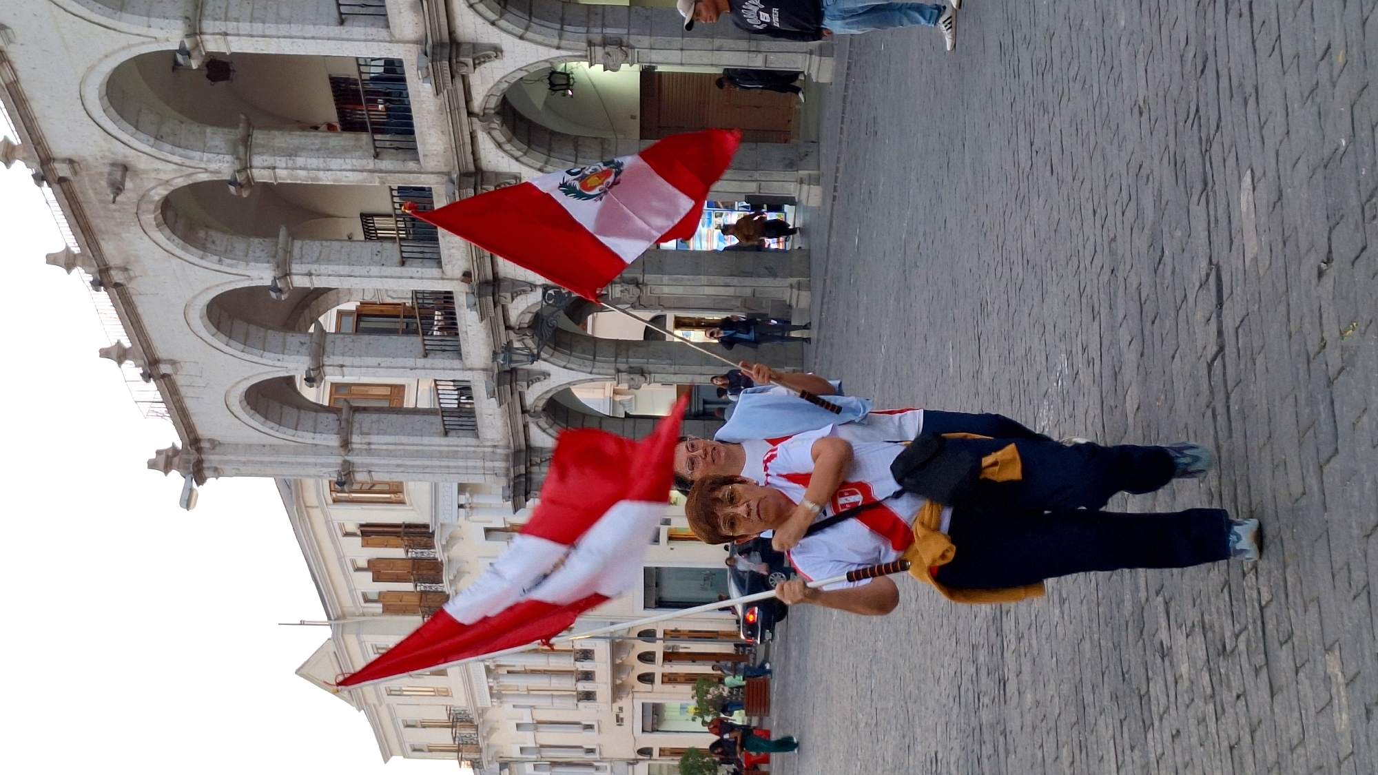 Two people display Peruvian flags in Arequipa plaza