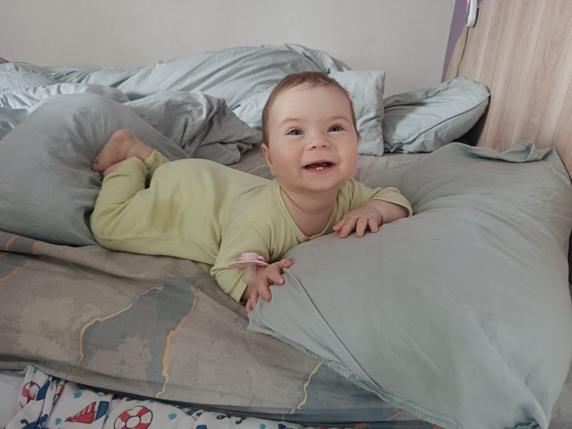 Baby in green onesie photographed smiling in Rusalevka, Russia