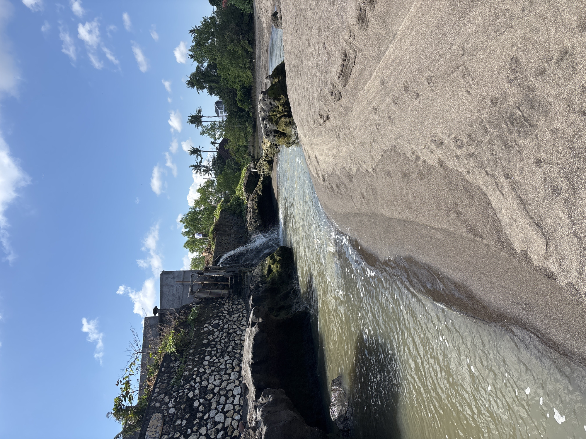 Calm riverbanks and a beached canoe in rural Mengwi