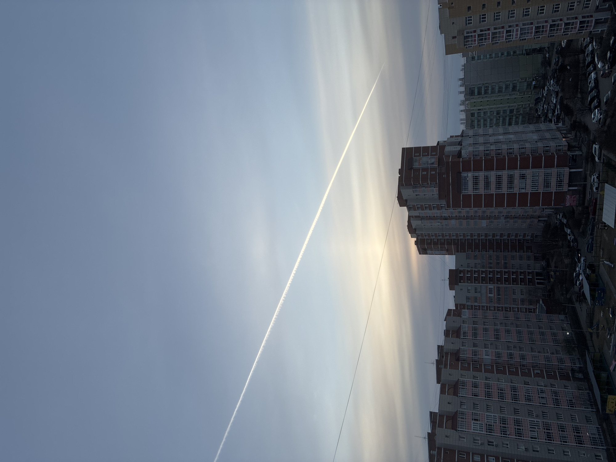 Aircraft contrail observed over apartment buildings in urban area