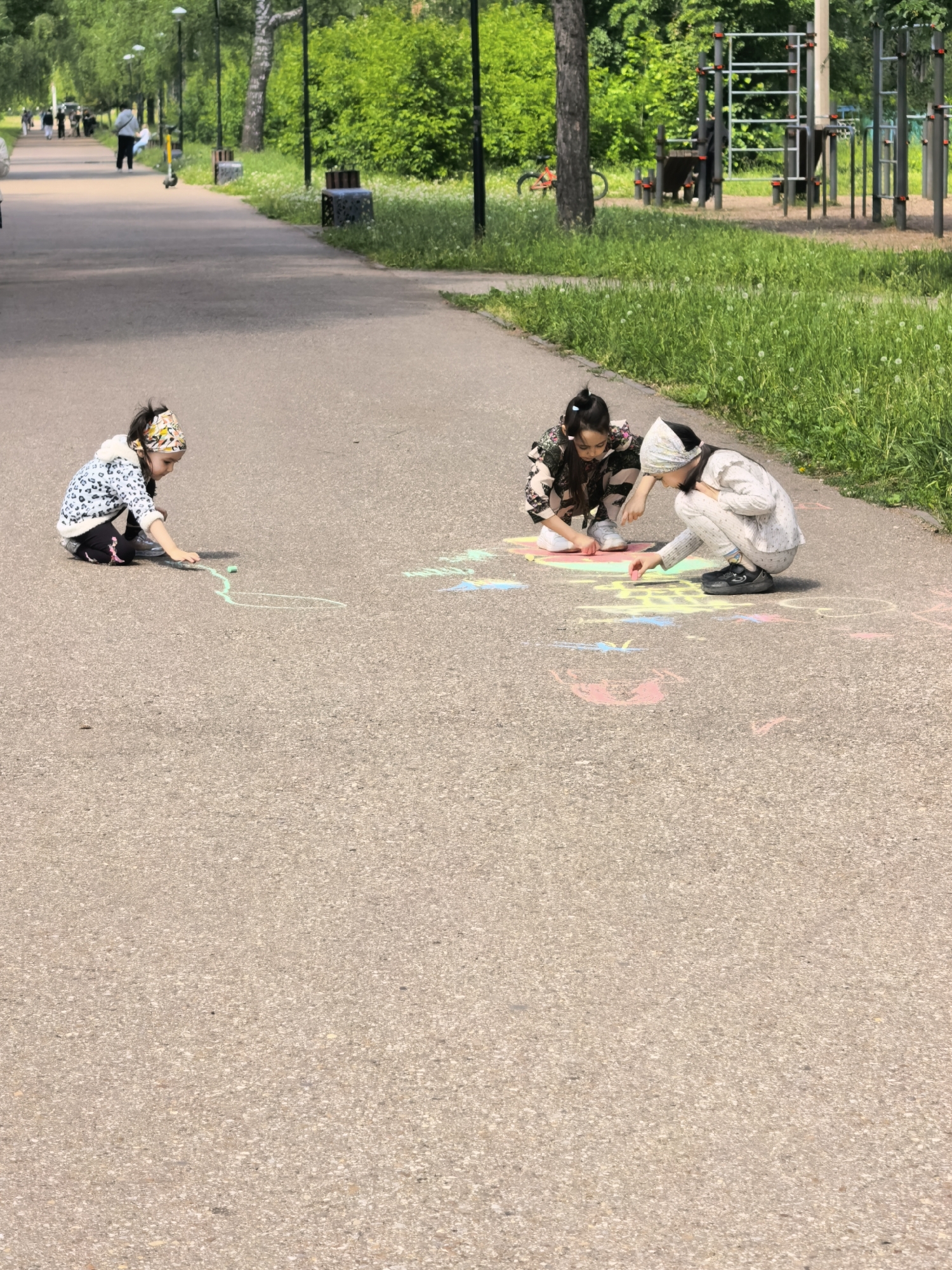 Woman takes selfies while children draw chalk art in Russian park
