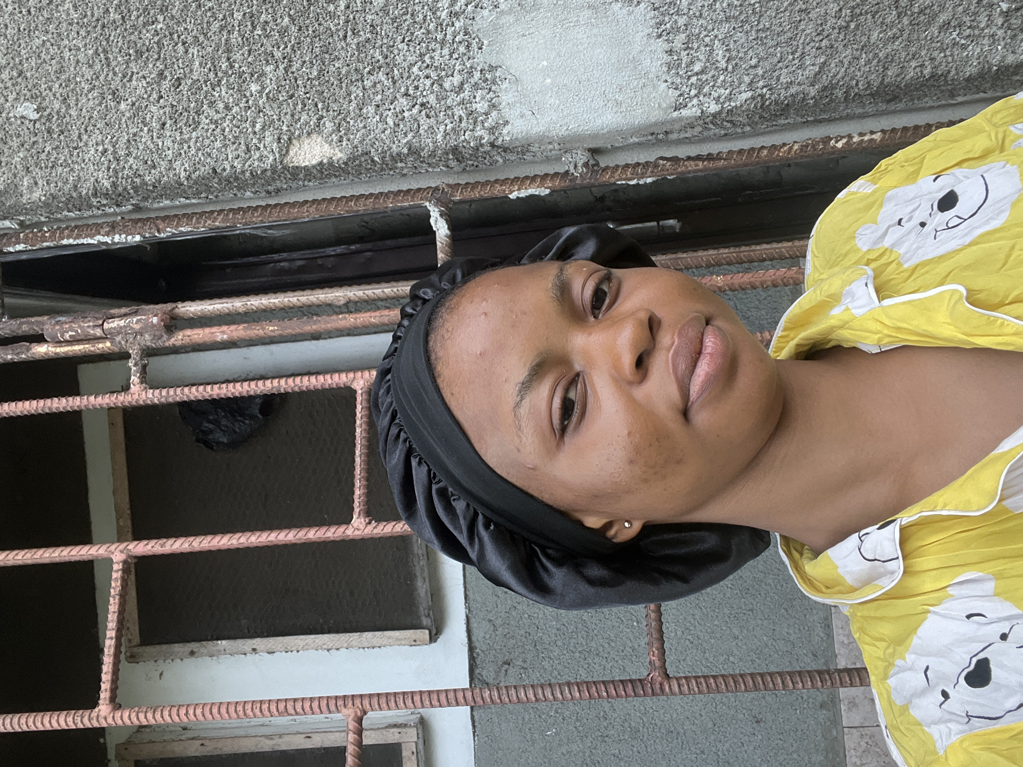 Woman in black bonnet collecting water in Lagos
