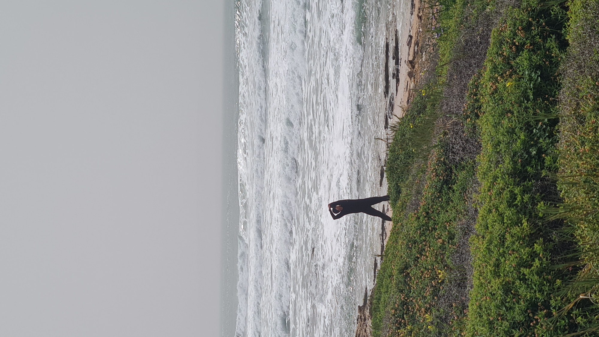 Surfers and beachgoers enjoy overcast Mediterranean coast near Nahariyya