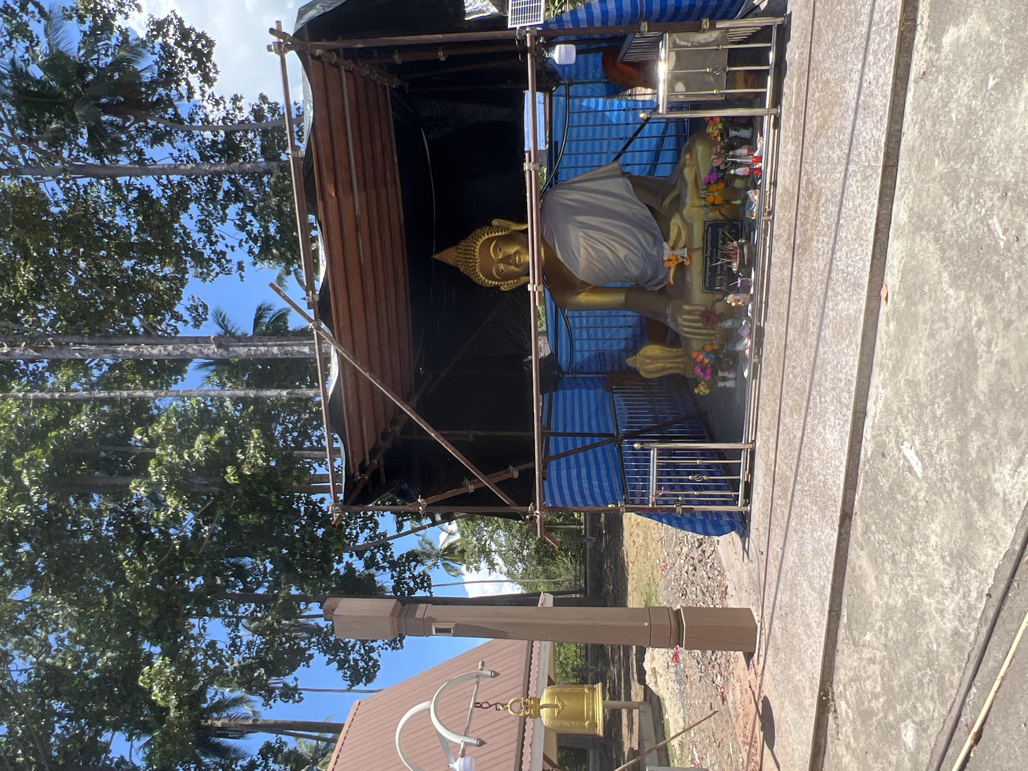 Buddha statue sheltered by temporary scaffolding structure in Thailand