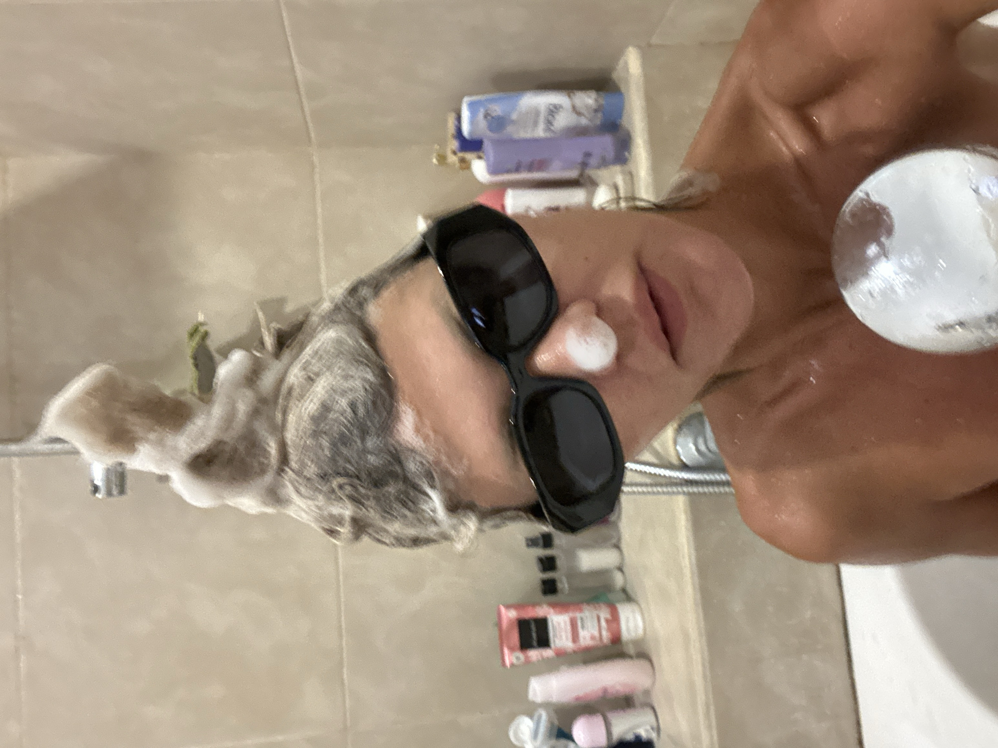 Person showers wearing sunglasses in North Kuta bathroom