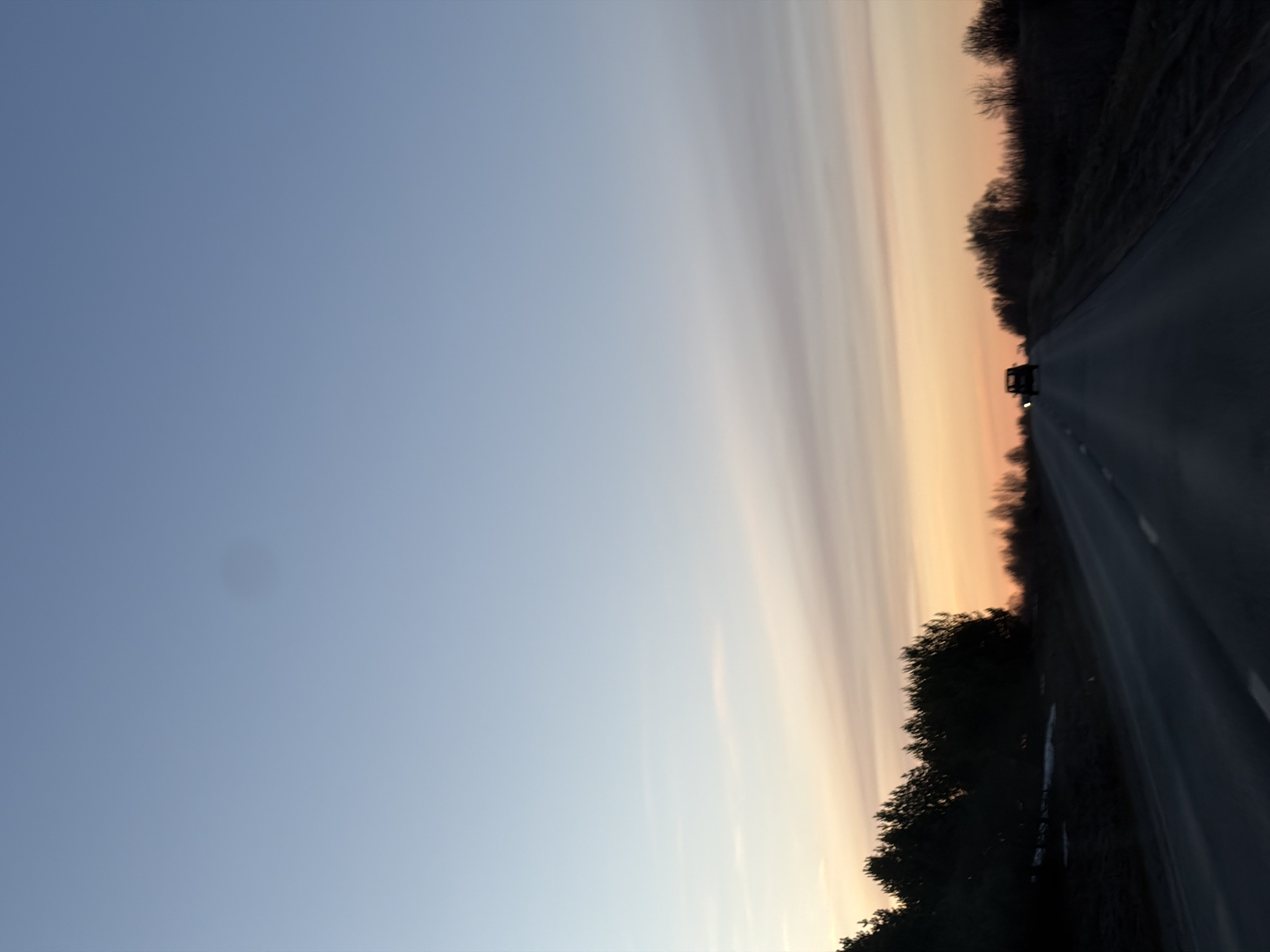 Sunset observed along tree-lined road in Foteni, Russia