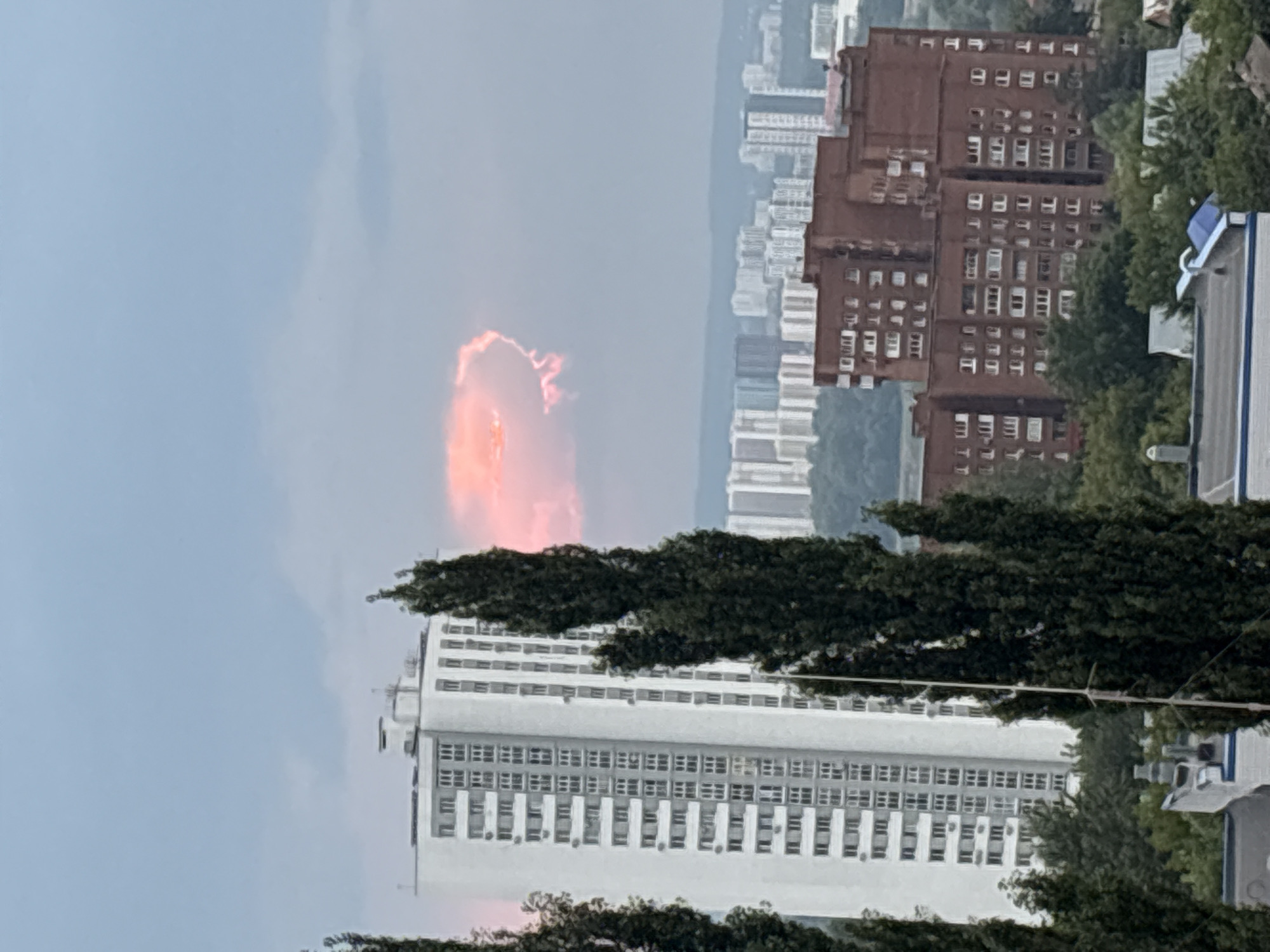 Ufa skyline with striking pink-orange clouds over city trees
