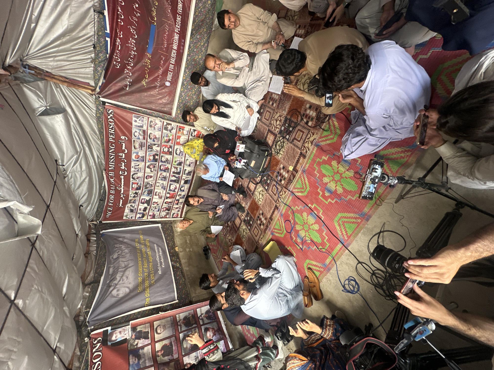Indoor gathering on patterned rugs beneath framed photographs