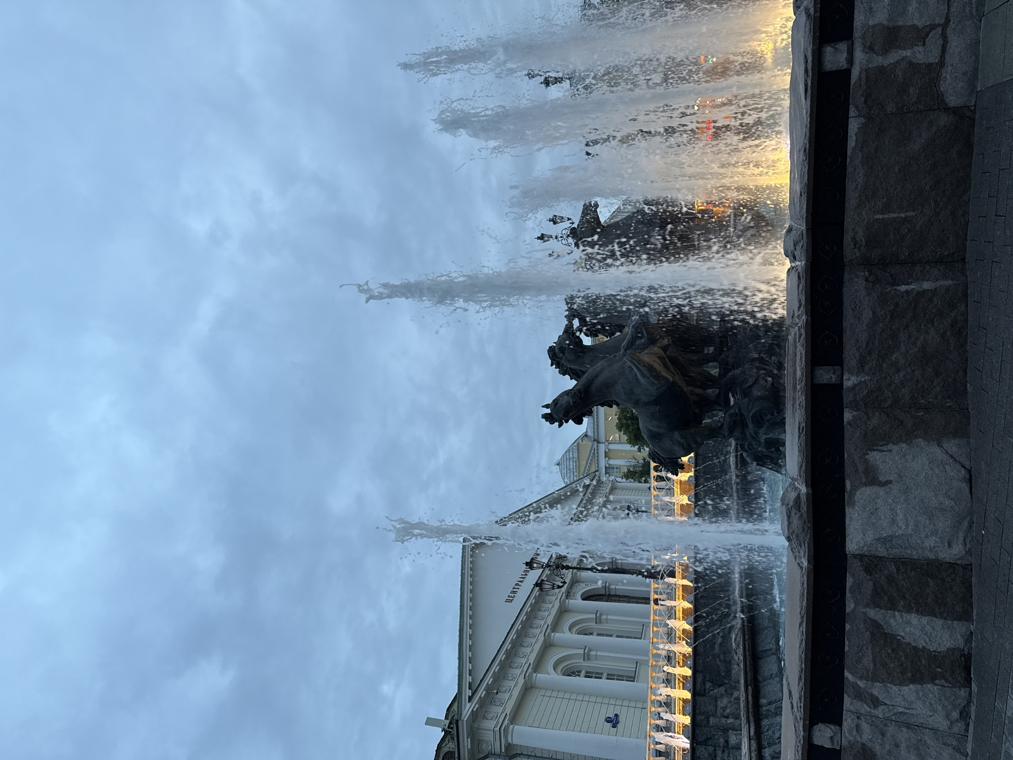 Tourists photograph Moscow's Manege Square fountain during evening visit