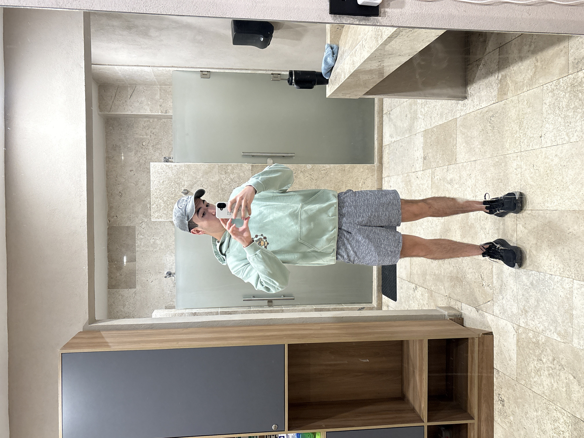 Mirror selfie in a Puebla restroom, mint green hoodie